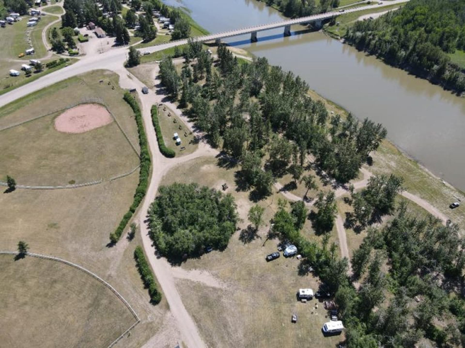Aerial view shows Tail Creek Park with campsites, trees, ball field, and nearby river.