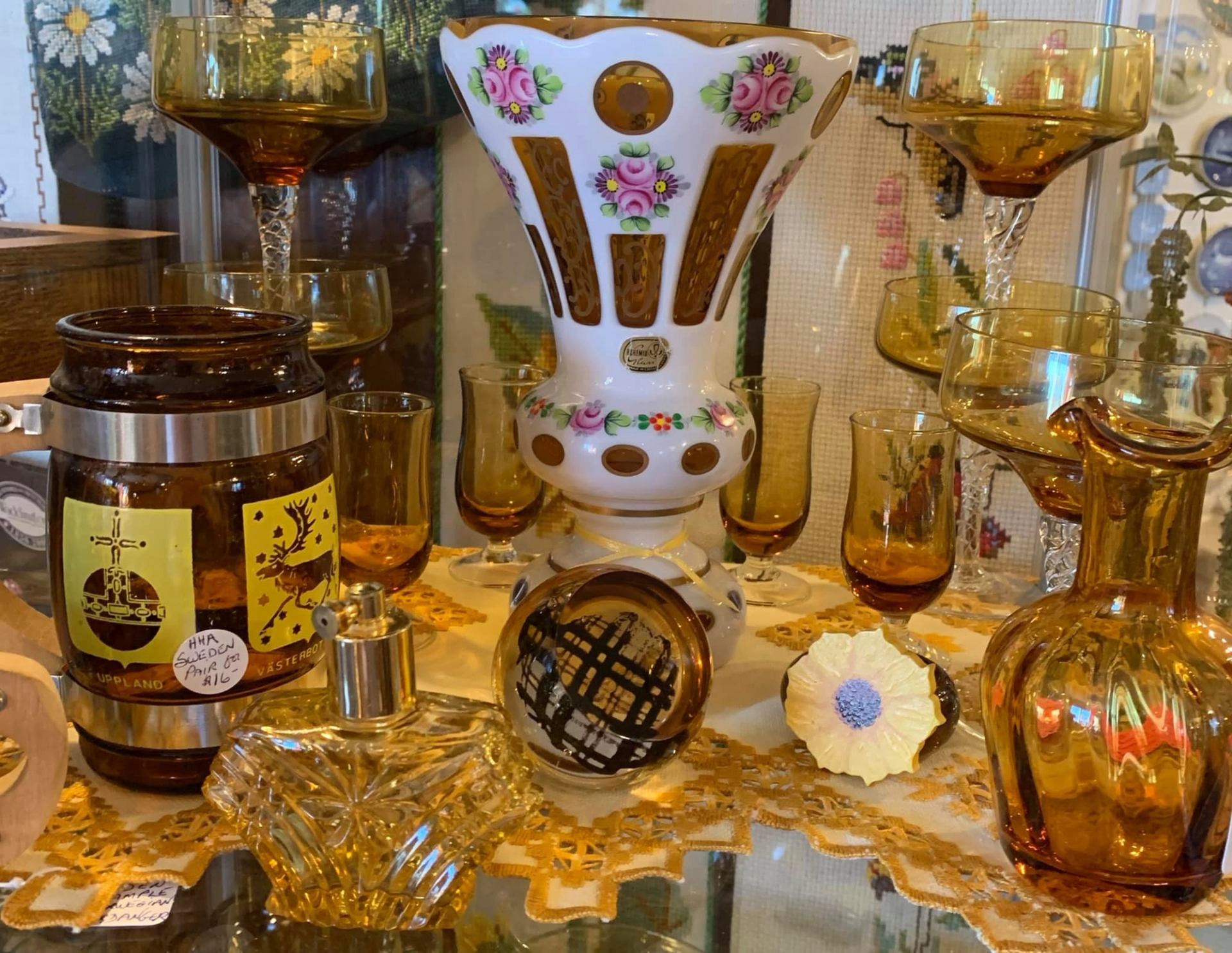 Amber and white vintage glassware displayed on a lace-covered shelf.