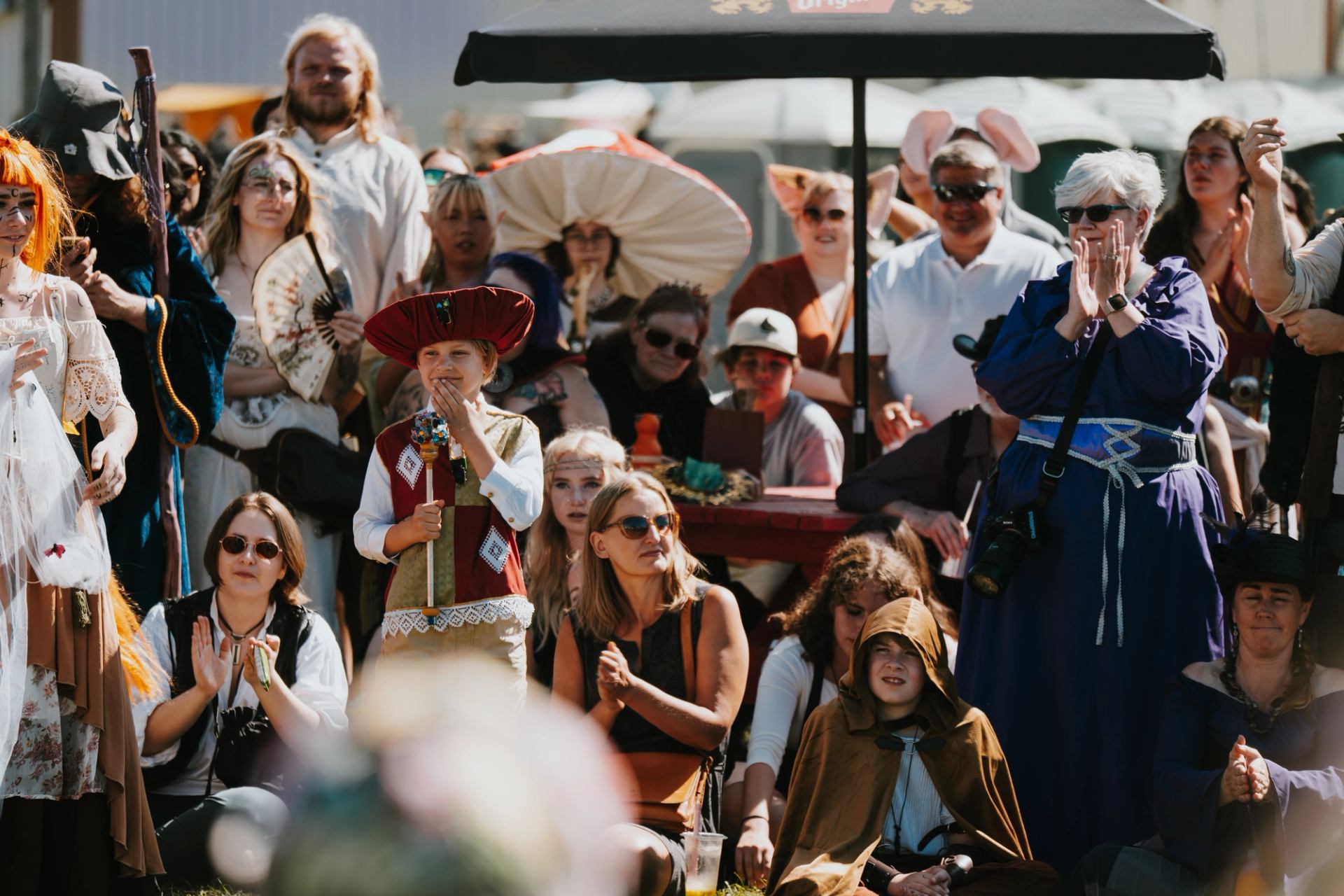 Group in diverse costumes gathered outdoors at a festive medieval-themed event.