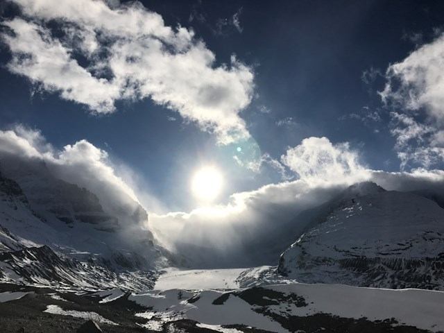 Scenic Lake Louise Parkway view with sunlit mountains beneath clear sky, captured during guided tour.