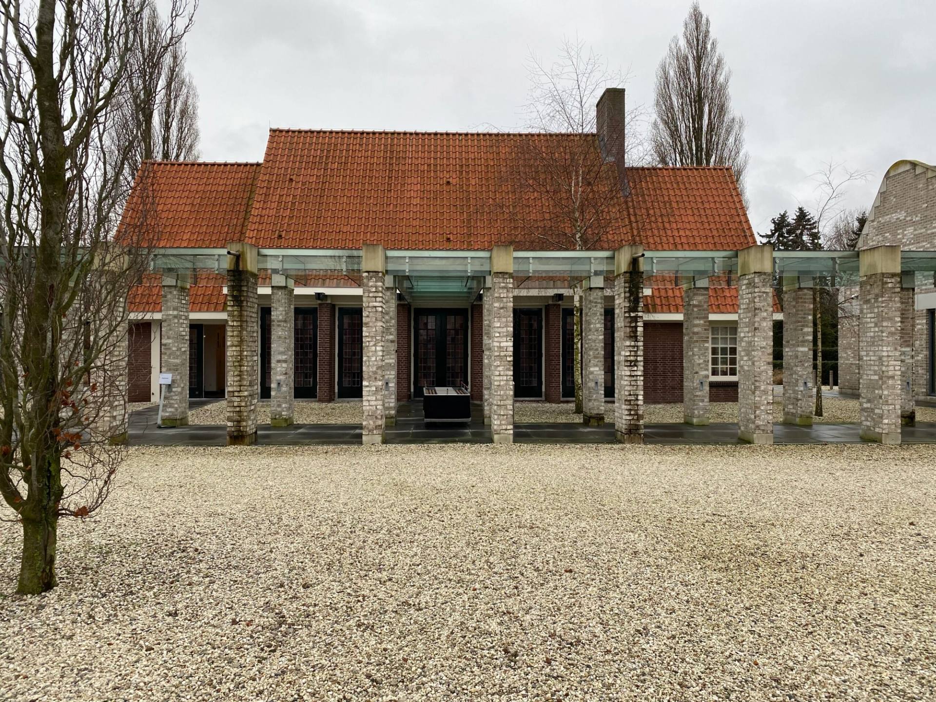 Het bakstenen gebouw van De Nieuwe Noorder met een rood pannendak, tussen het groen