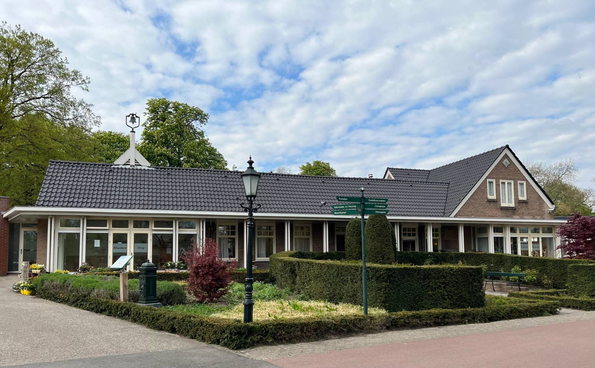 Het lage gebouw van Westerveld in Driehuis, met een lantaarn en lage hagen ervoor