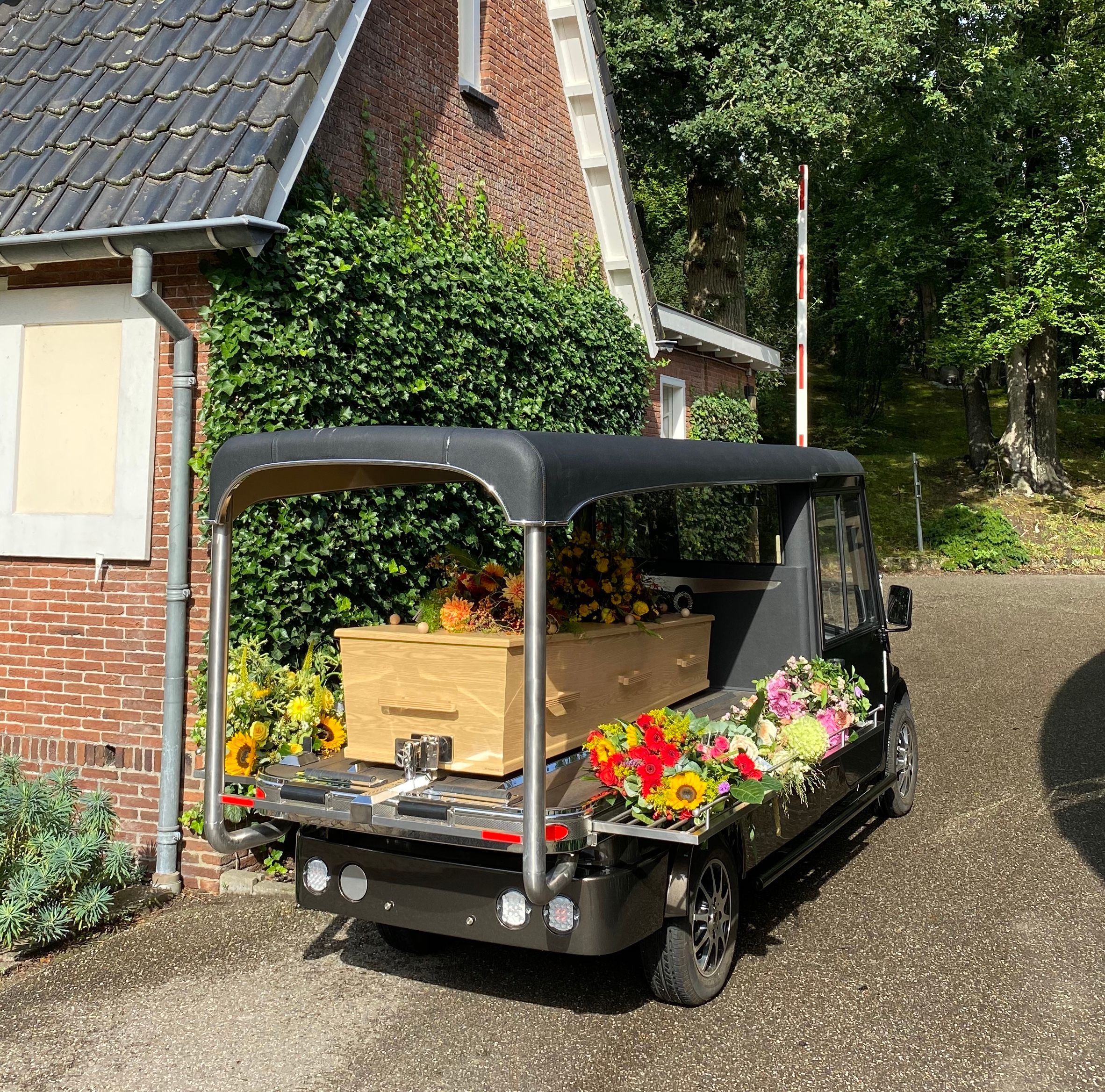 De elektrische rouwwagen van Westerveld met kist en bloemen