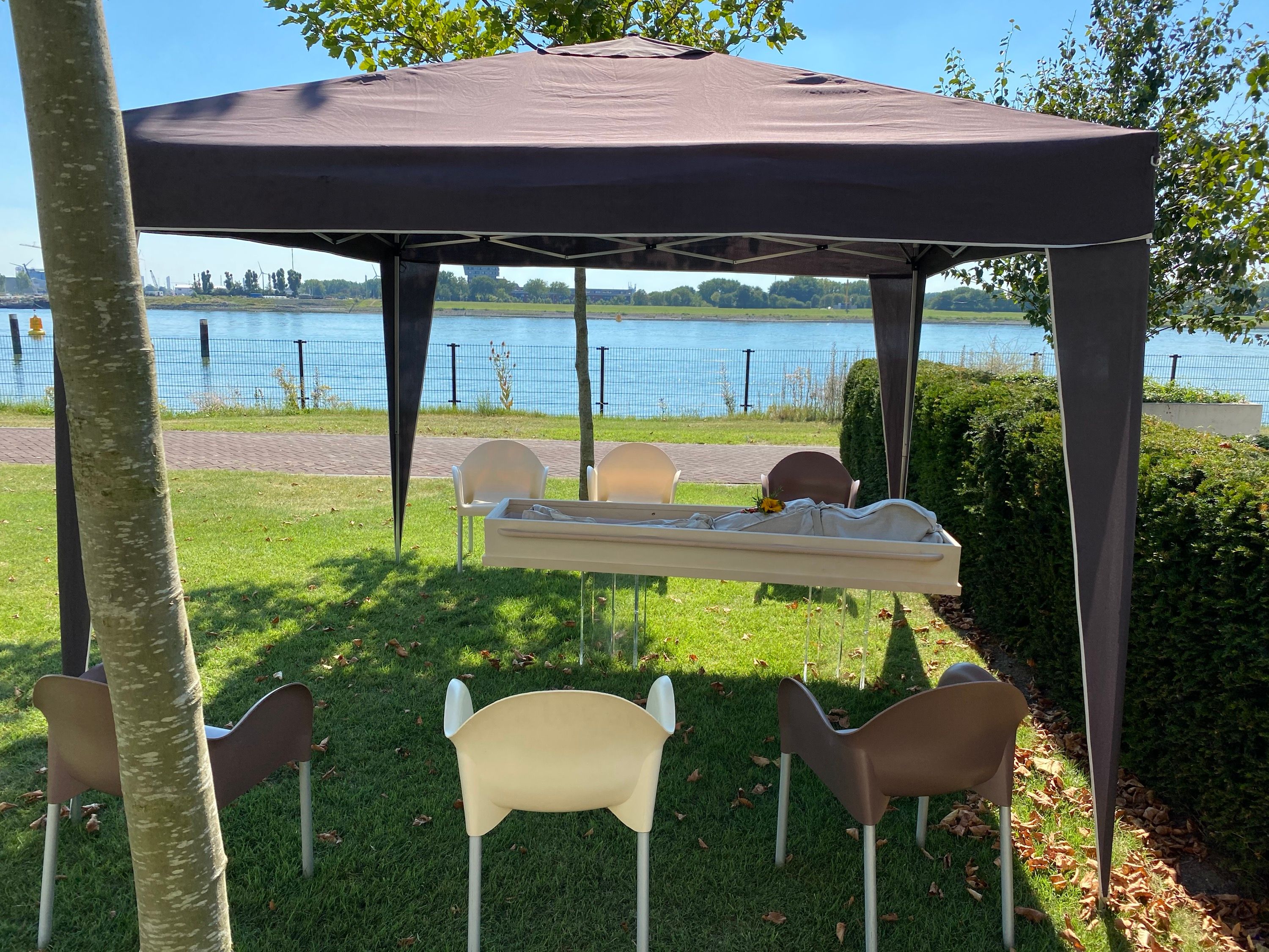Een tent aan het water met stoelen in rijen en een opbaring vooraan