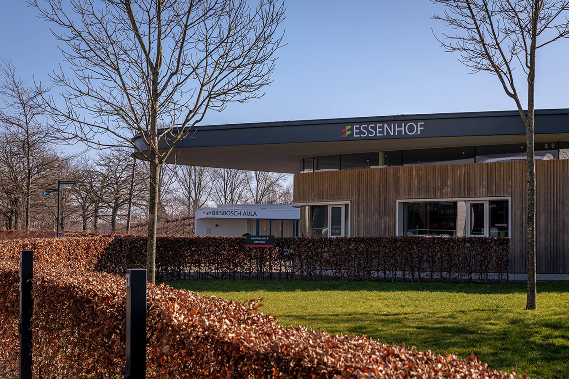 Het houten gebouw van de Essenhof in Dordrecht, achter een beukenhaag