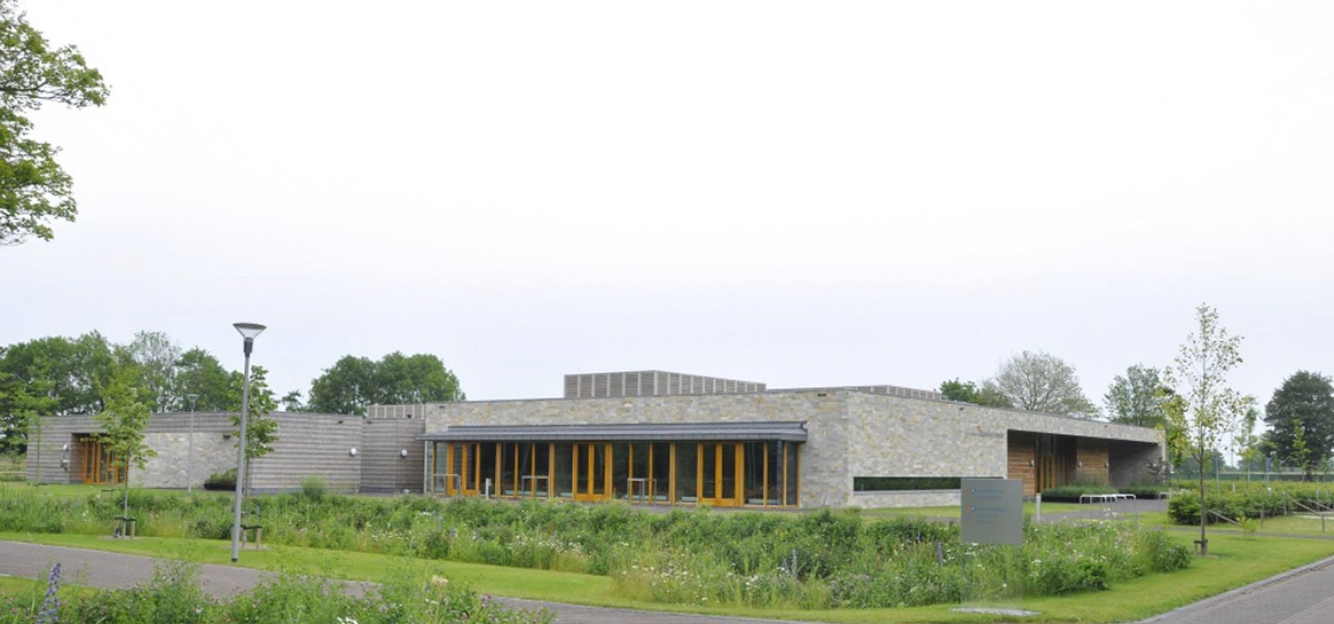 Het lage gebouw van Crematorium Waerdse Landen, met een begroeid dak en gras ervoor
