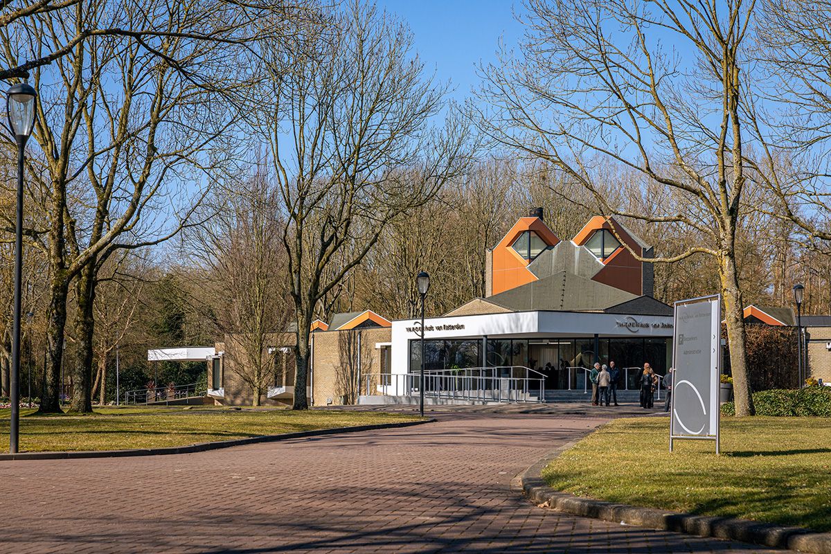 Het gebouw van Laurentius in Rotterdam, met een oranje dak tussen de kale bomen