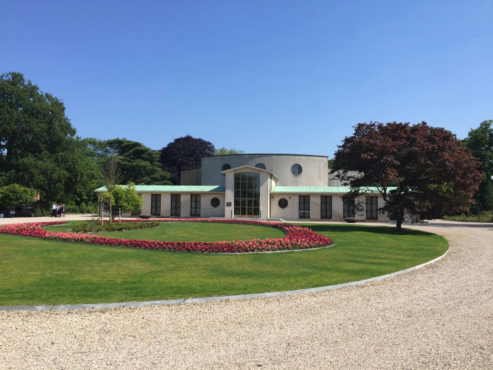 Het gebouw van De Nieuwe Ooster achter een rond bloemperk met rode bloemen