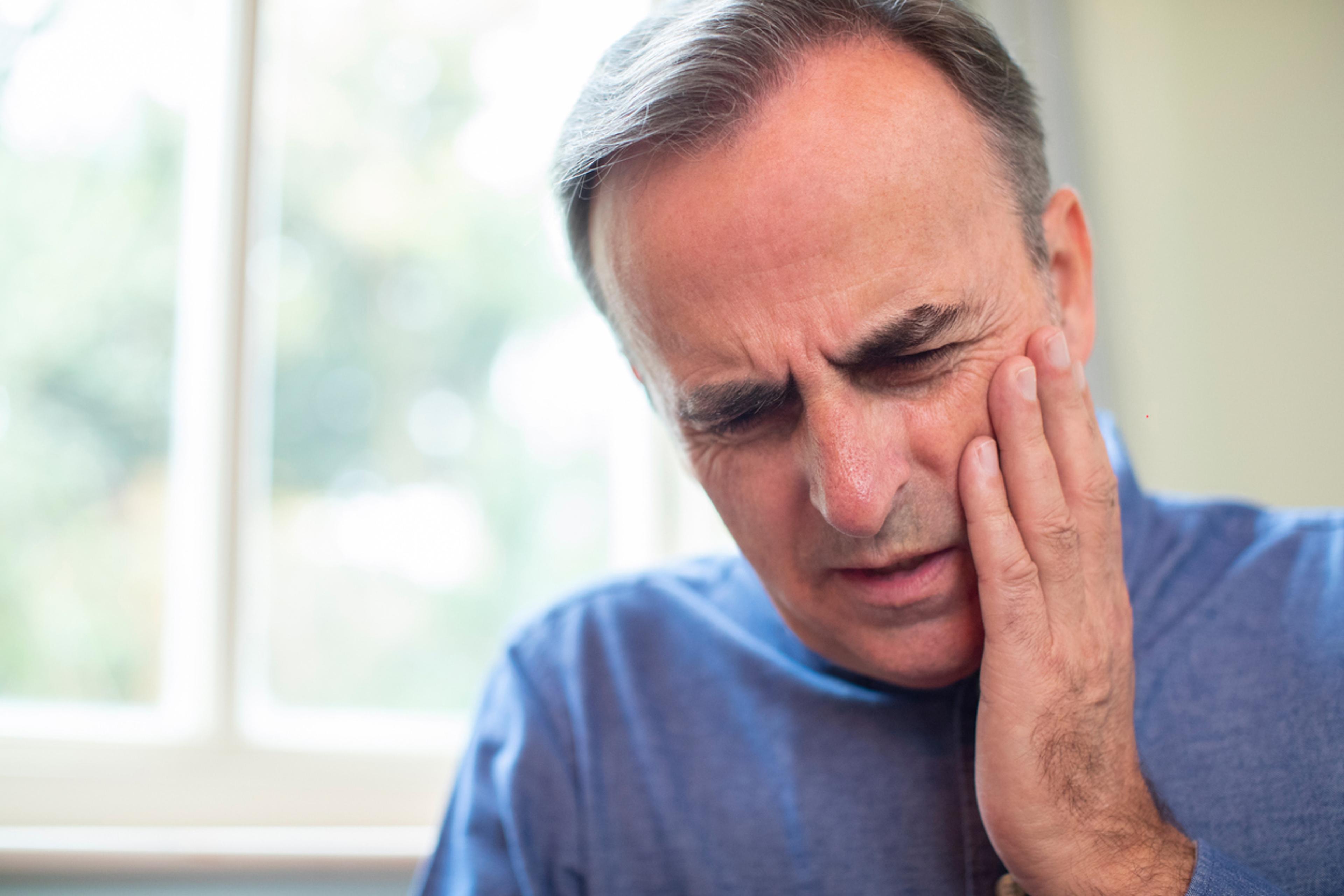 Person holding their cheek in pain