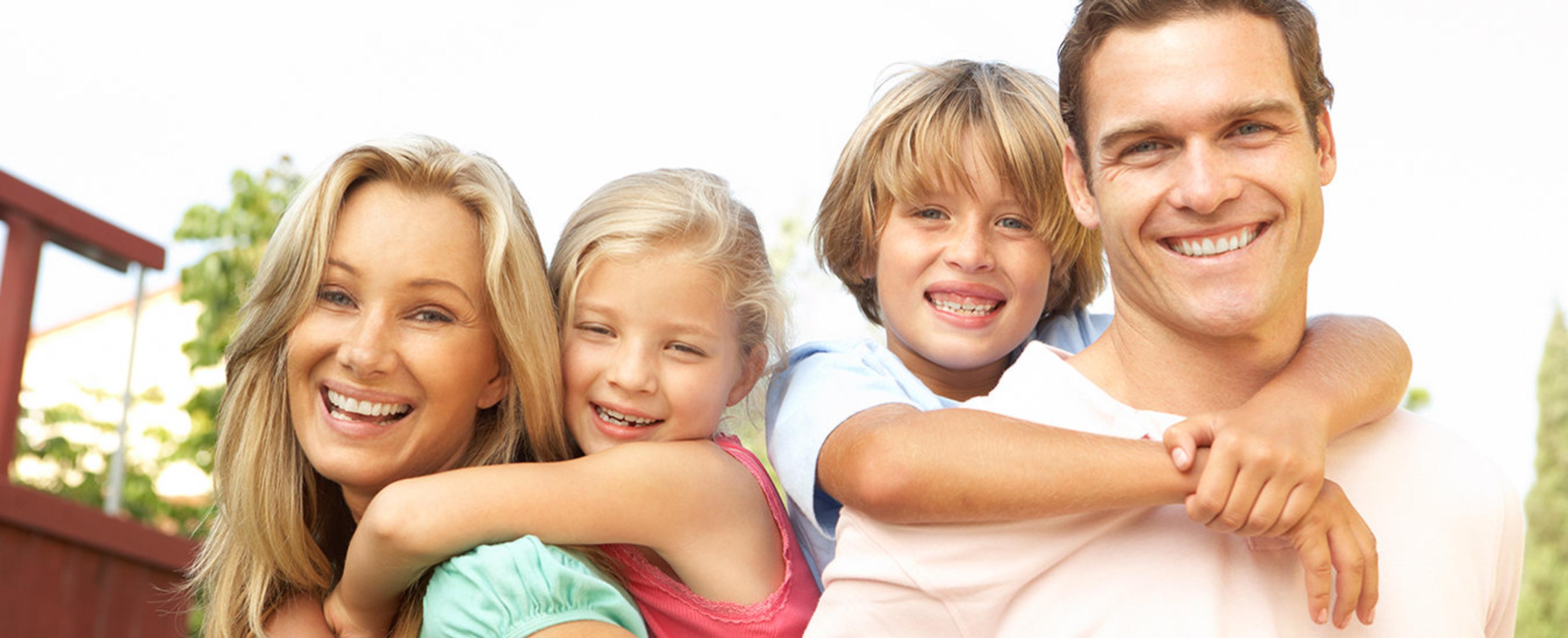 A family of four smiling together outdoors