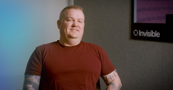 ビデオインタビューに答えるInvisibleのセキュリティ責任者。背景の壁にInvisibleのロゴ