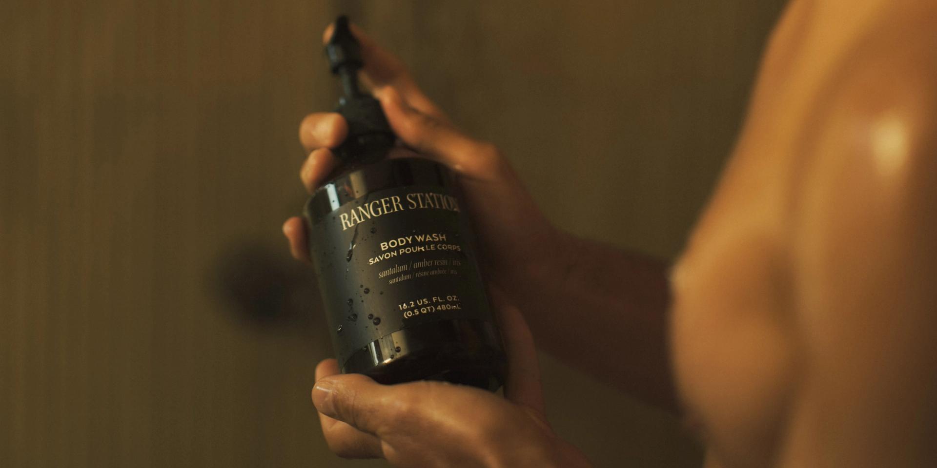 Man in shower looking at Ranger Station Santalum Body Wash in his hands