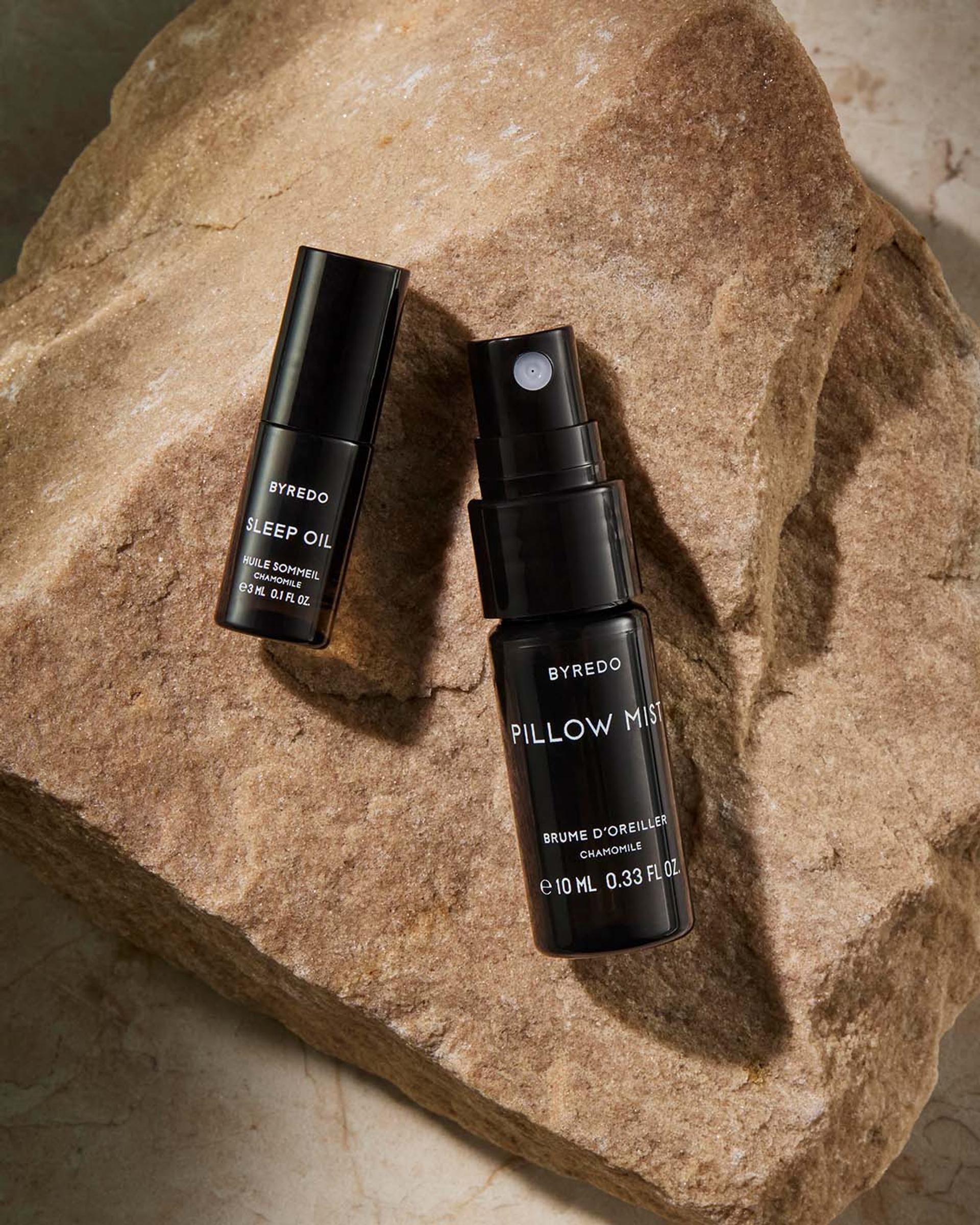 Byredo Sleep Oil and Pillow Mist bottles on a rock