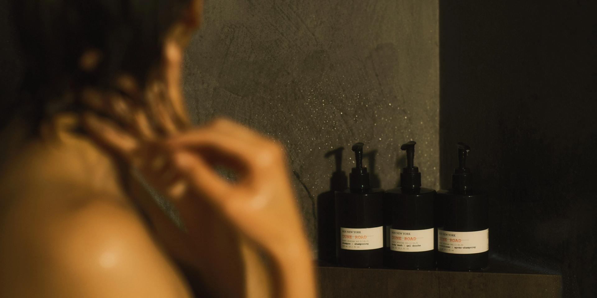 Woman in shower washing hair with MiN New York Dune Road Shampoo