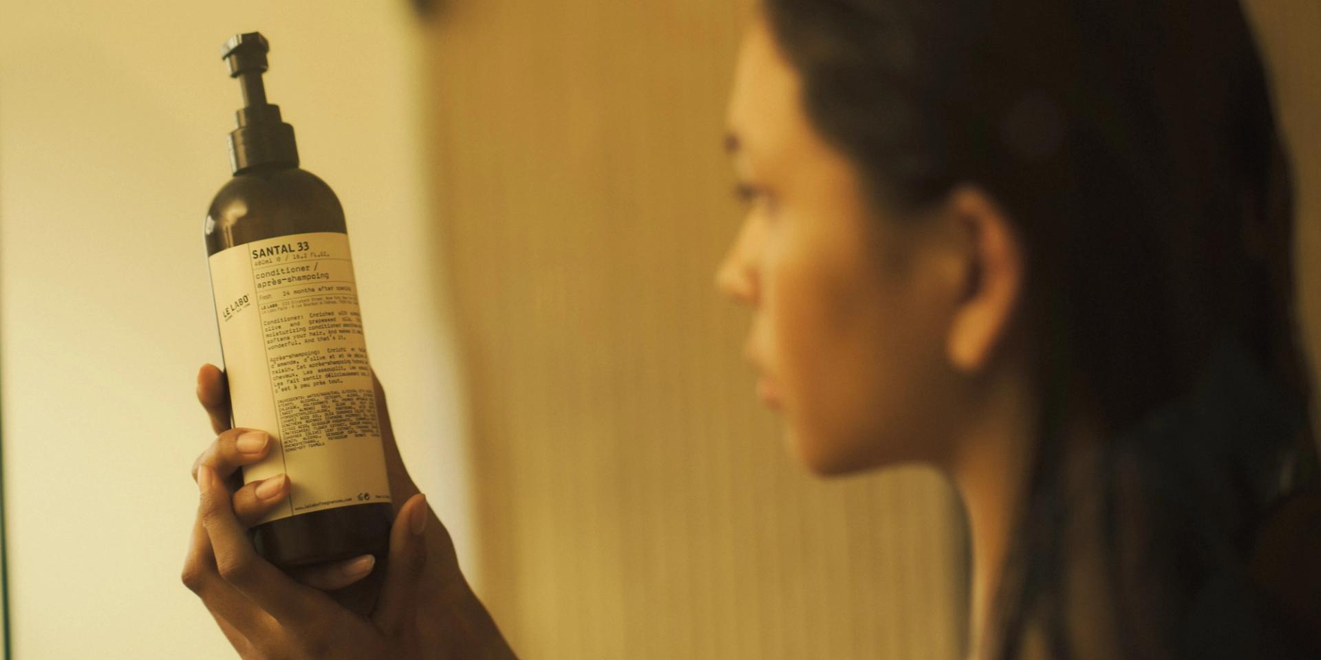 Woman in shower holding Le Labo Santal 33 Conditioner in hands