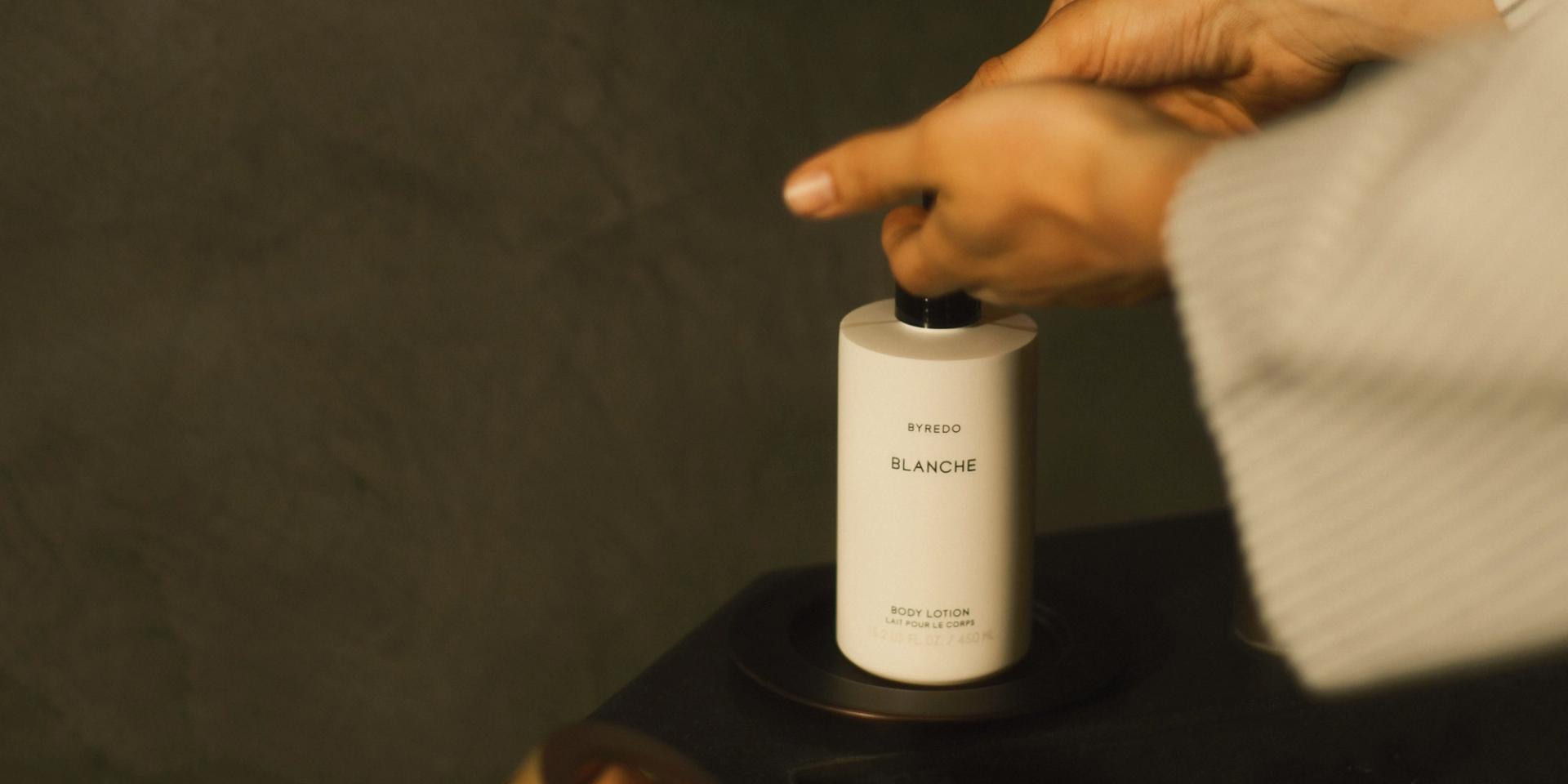 Girl pumping bottle of Byredo Blanche Body Lotion on vanity