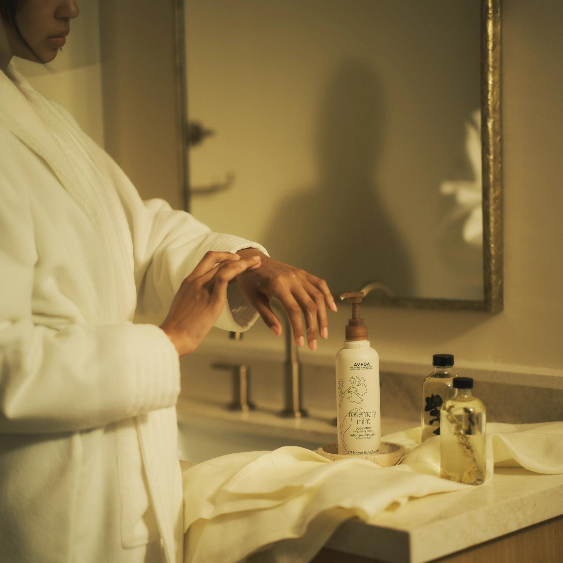 Aveda Rosemary Mint Body Lotion on Bathroom Countertop with girl in robe