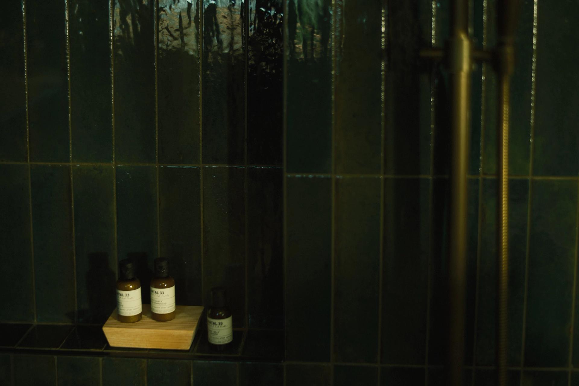 Le Labo Santal 33 Shampoo, Conditioner and Shower Gel single-use amenities on shower shelf