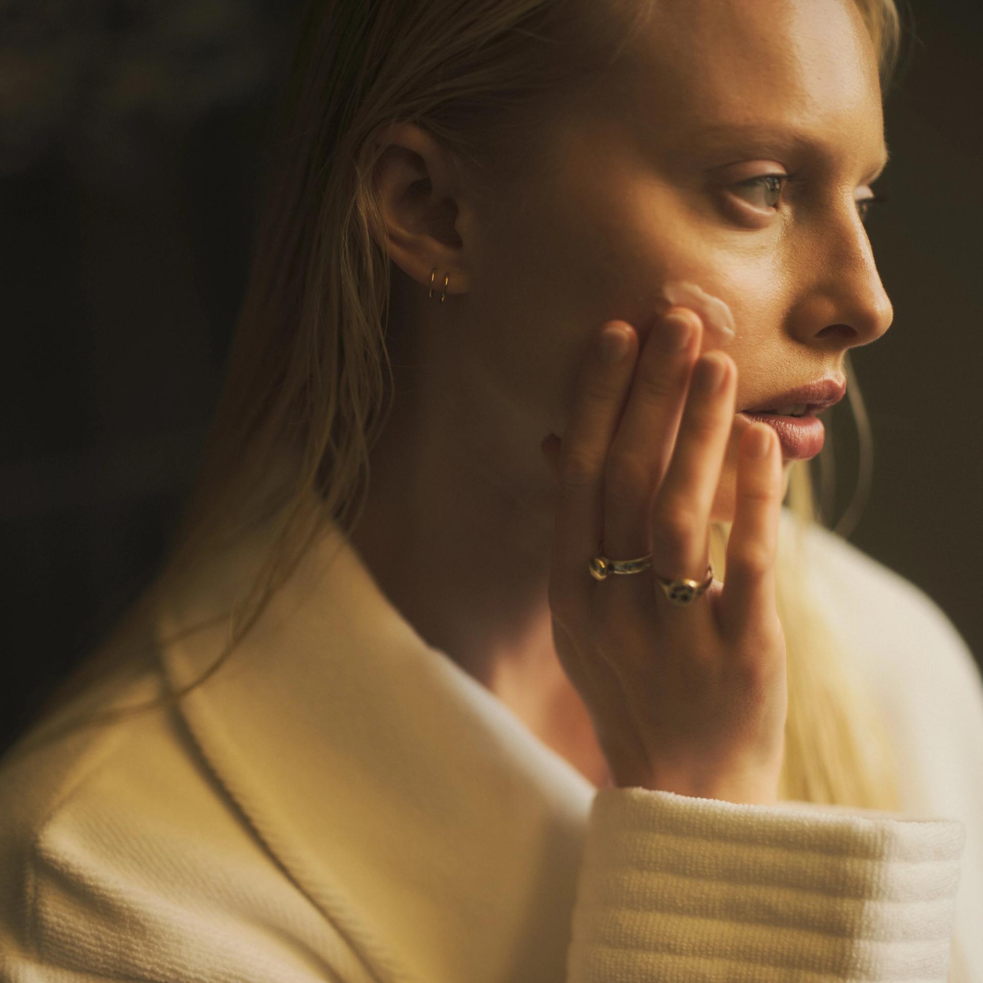 Woman in robe applying face cream