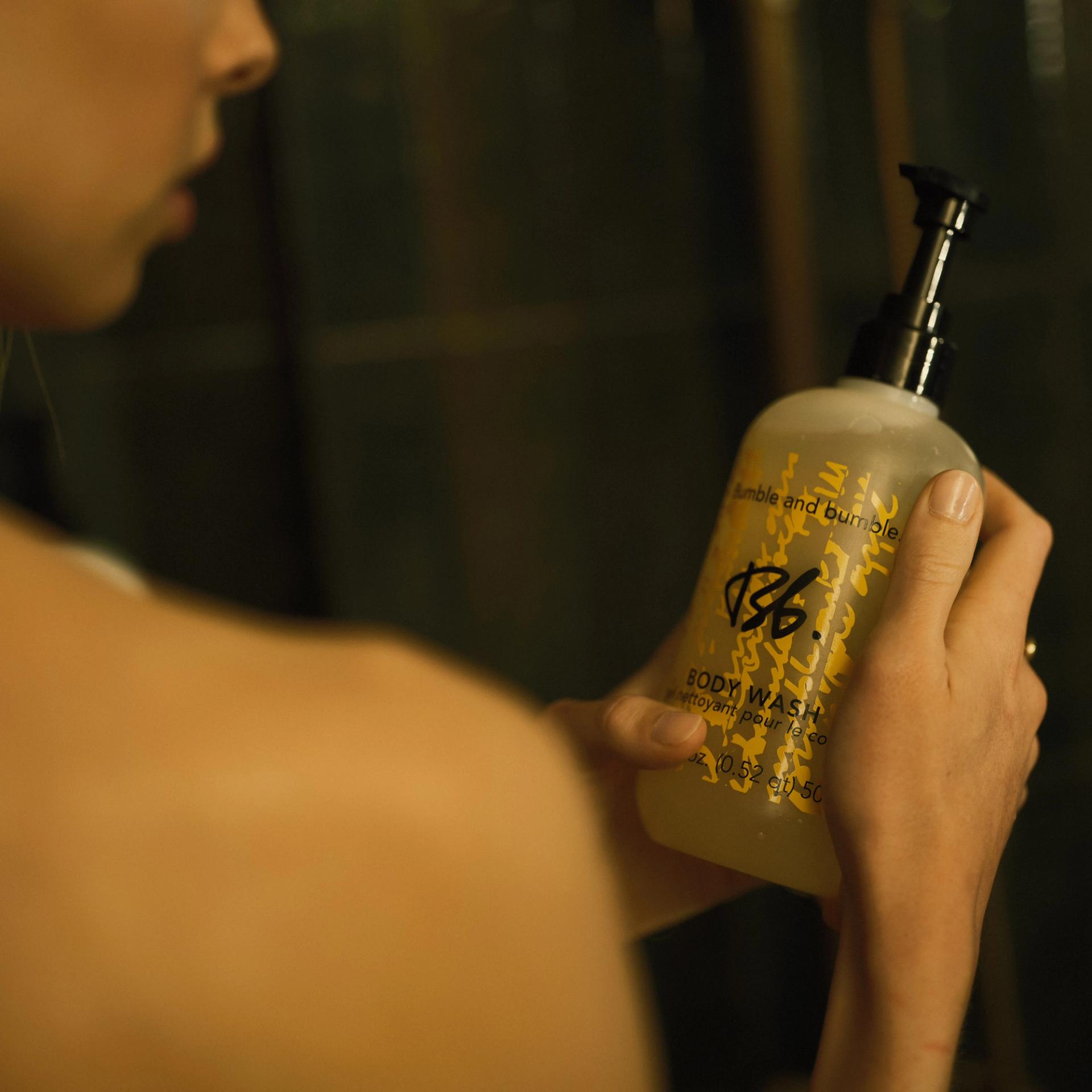 Girl holding a bottle of Bumble & Bumble Body Wash in the shower