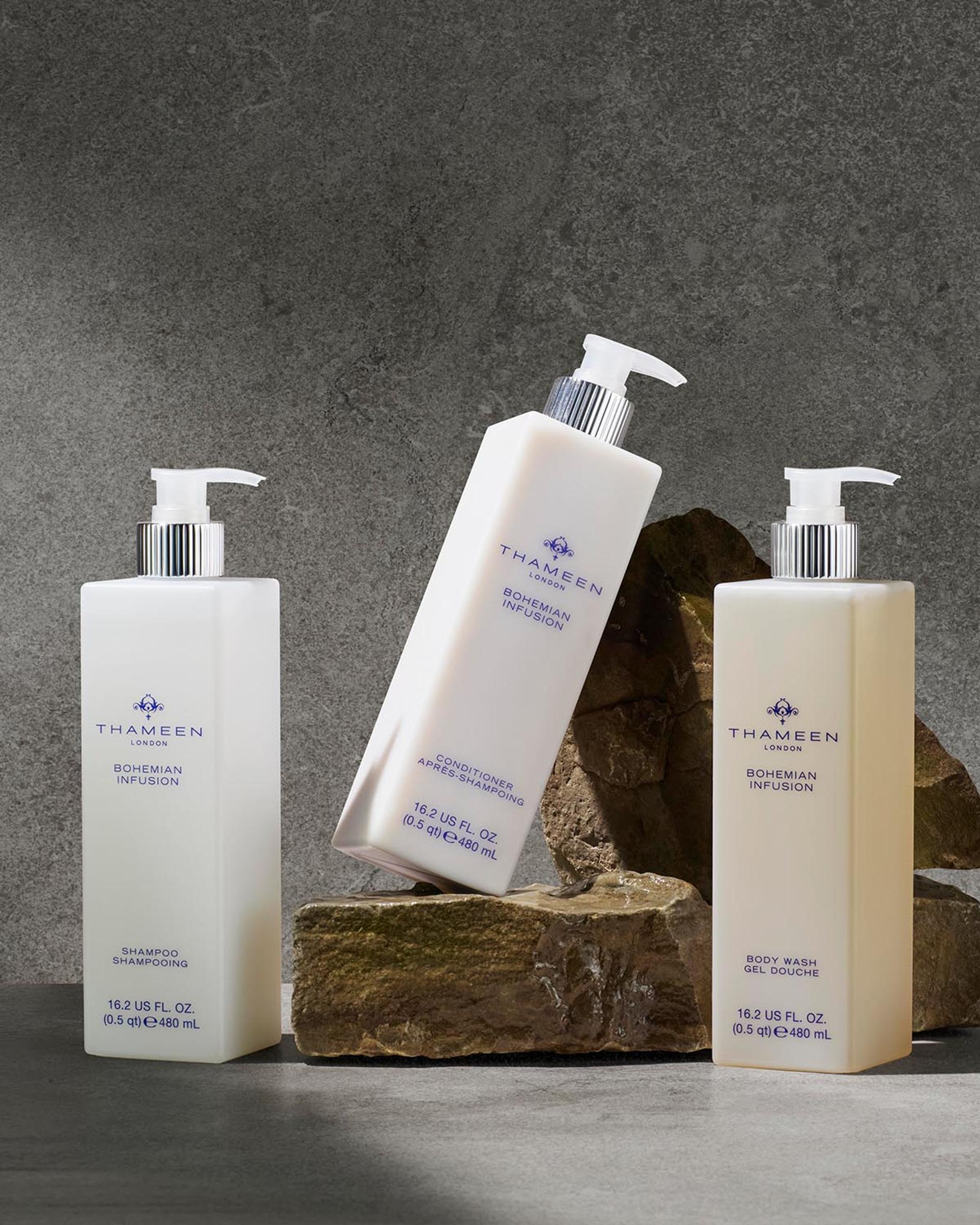 Thameen London Bohemian Infusion Shampoo, Conditioner, and Body Wash dispensers on bathroom vanity with stone