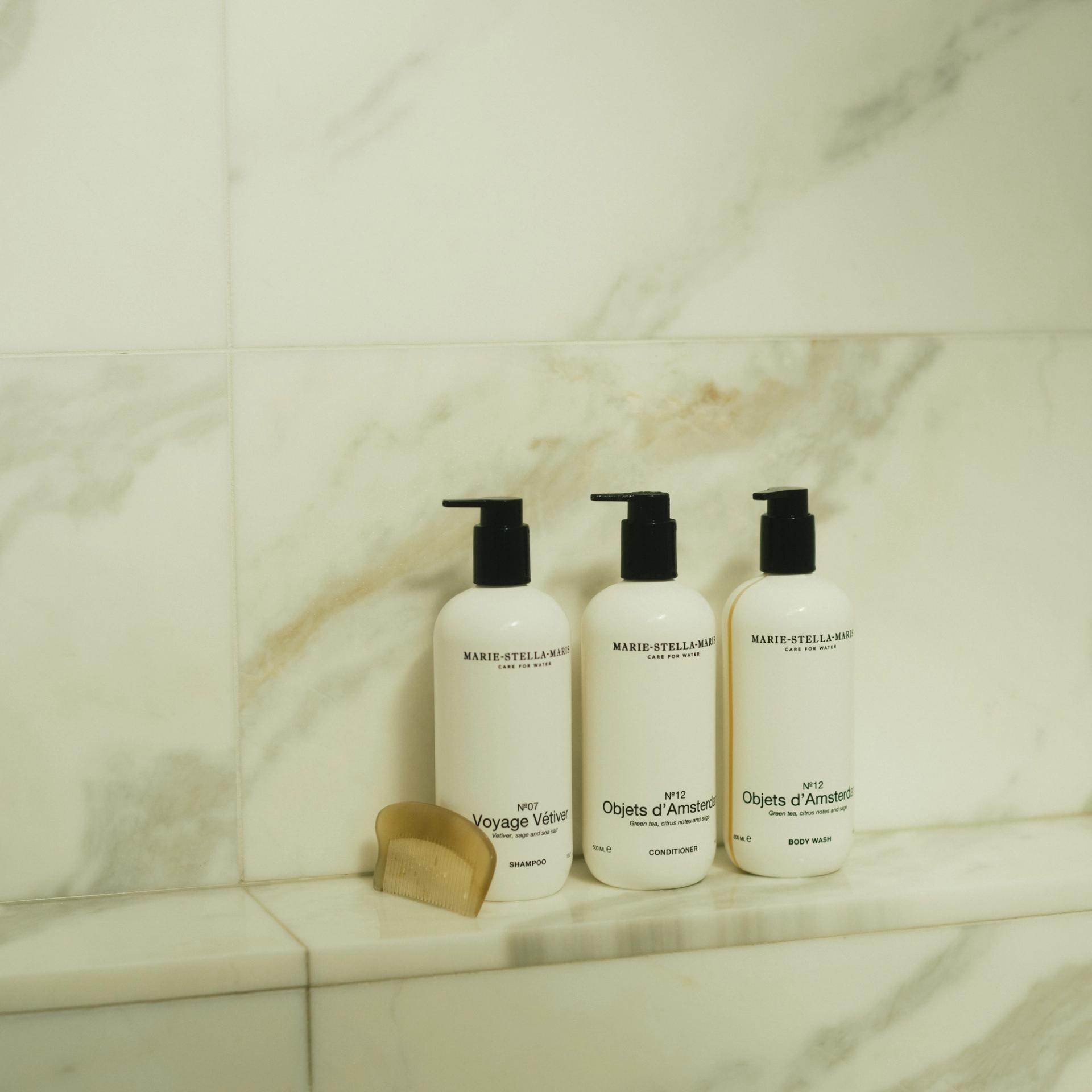 Marie Stella Maris Objets d'Amsterdam Shampoo, Conditioner and Body Wash dispensers on marble shower shelf