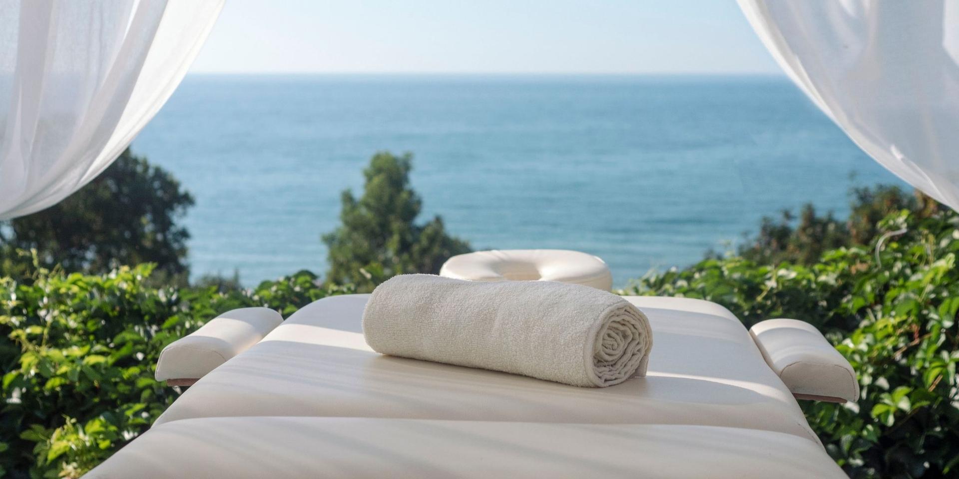 Image of massage bed outdoors with water in the background and beautiful greenery