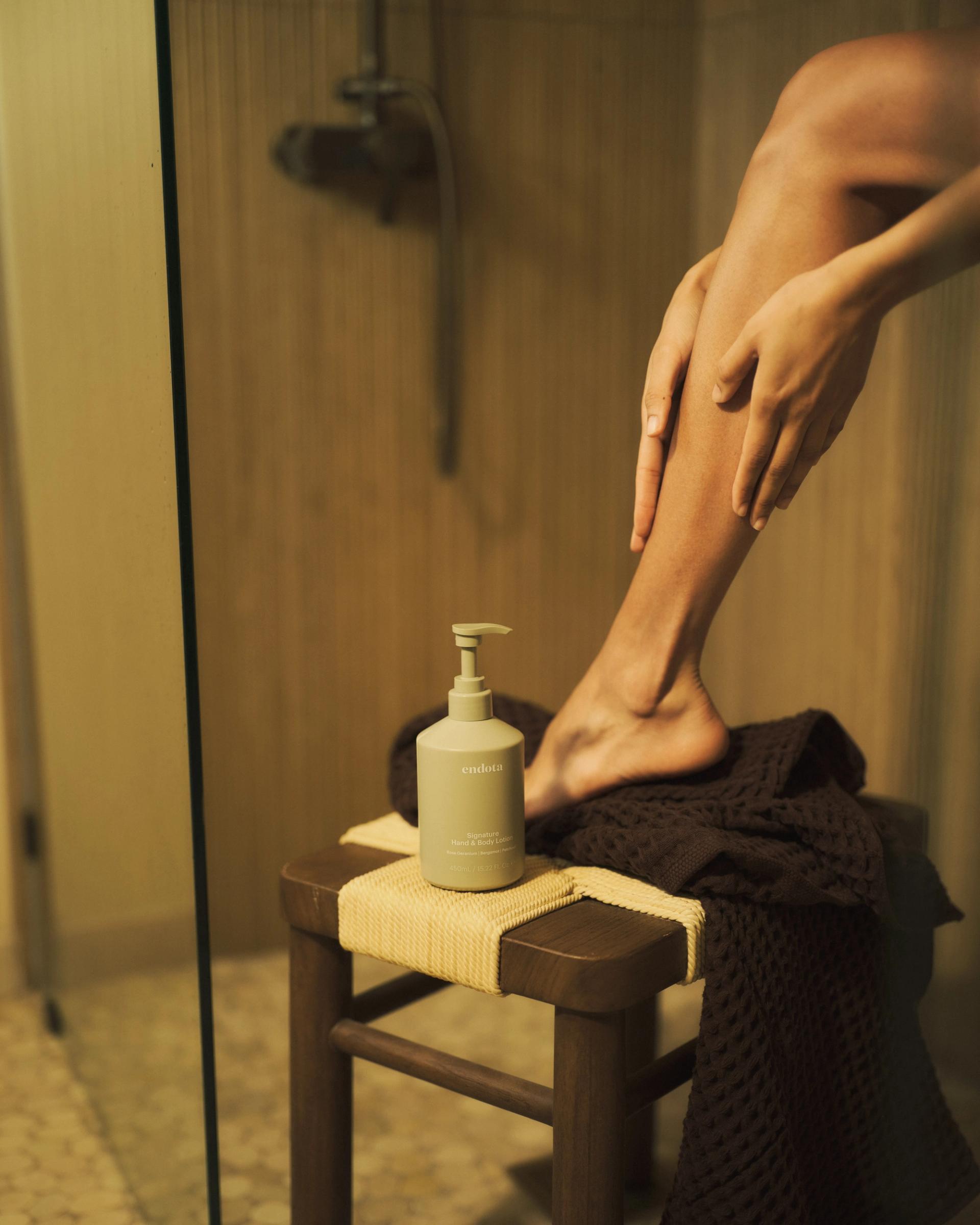 Girl applying endota Signature Hand & Body Lotion in shower