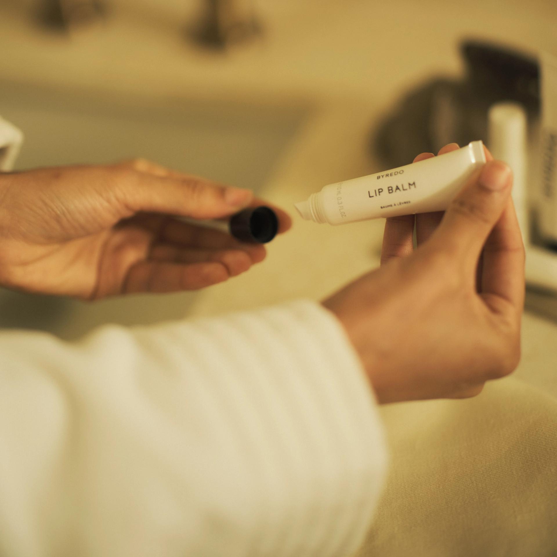 Girl holding Byredo Lip Balm tube with cap off