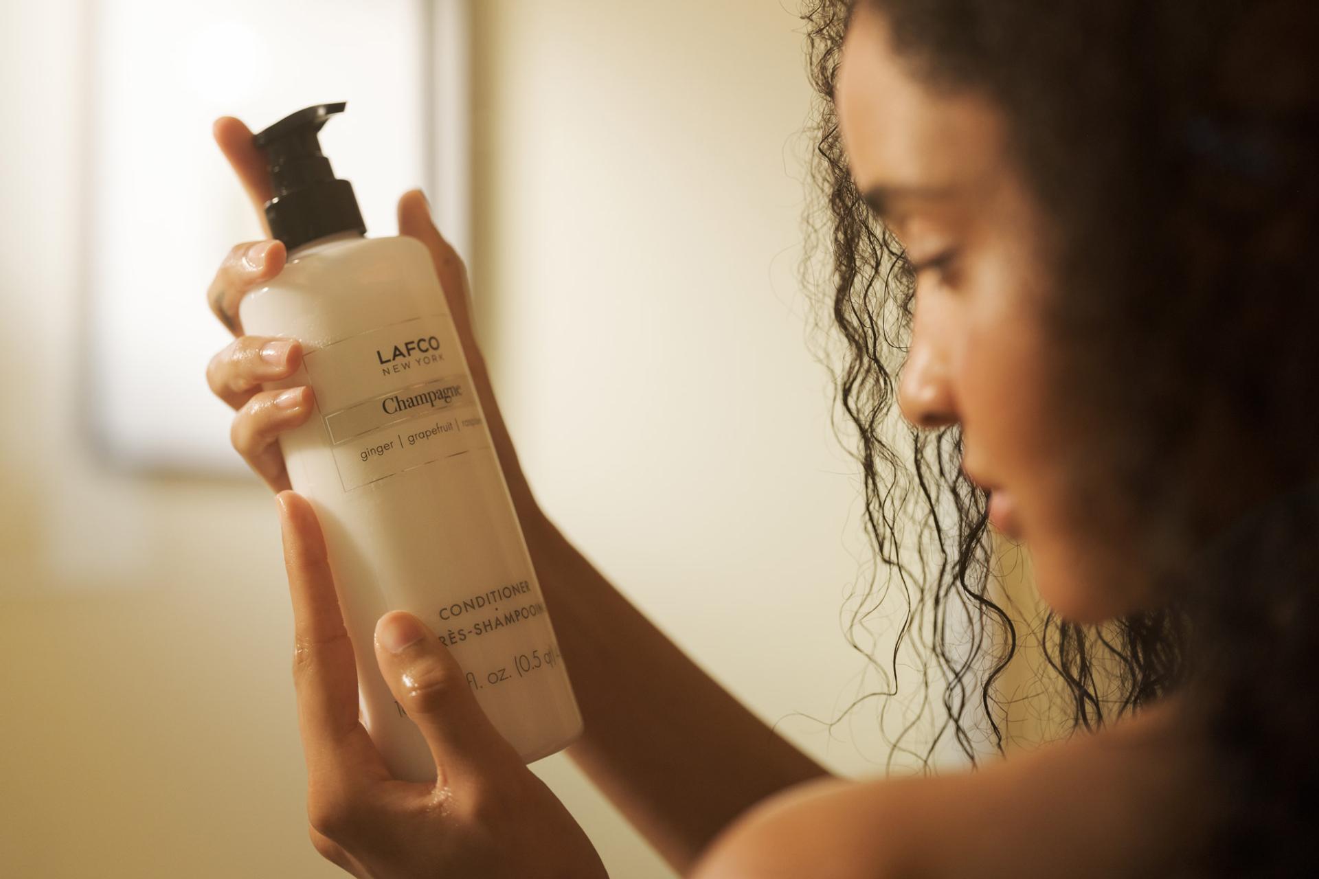Girl holding Lafco Champagne Conditioner in the shower