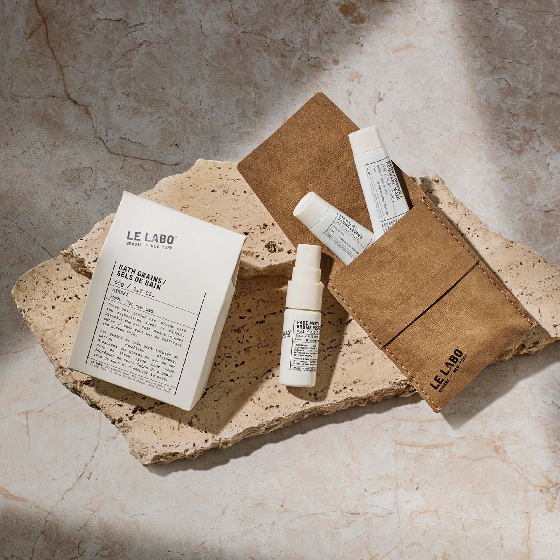 Le Labo Hinoki Bath Grains, Le Labo Basil Face Mist and Hand Pomade, and Lip Balm on counter