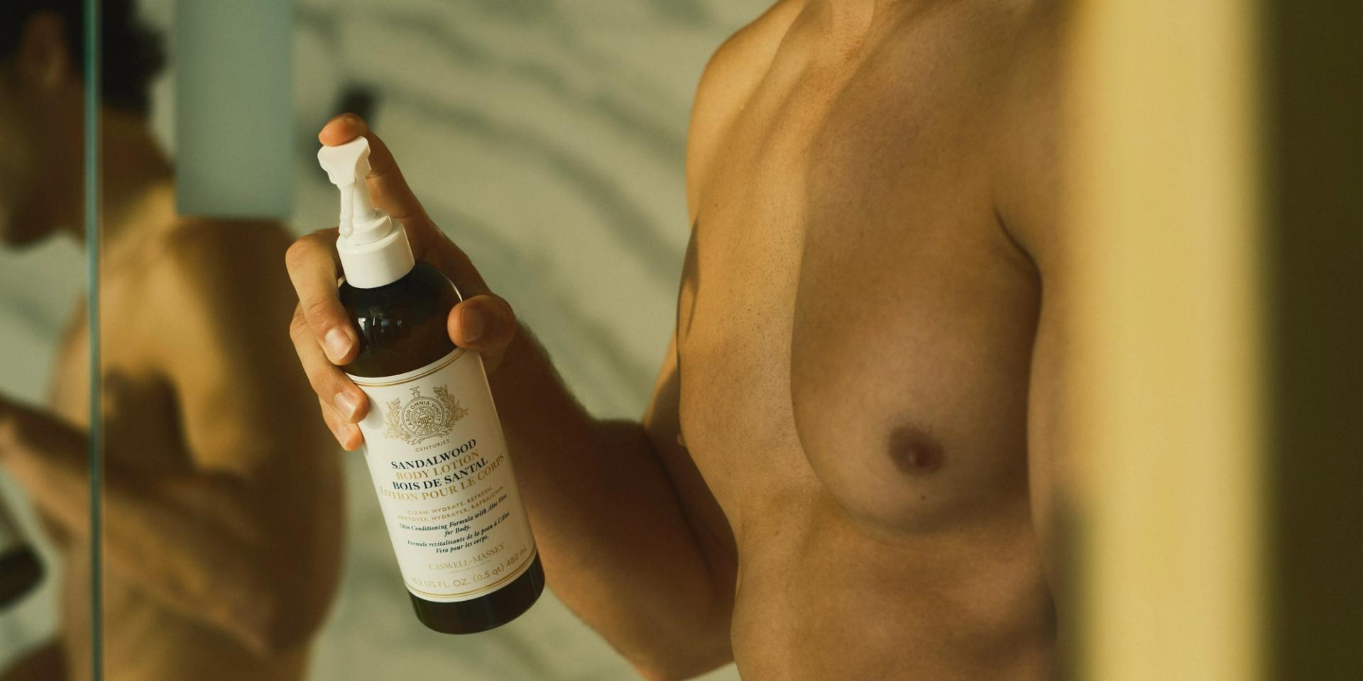 Guy pumping bottle of Caswell-Massey Sandalwood Body Lotion in Bathroom