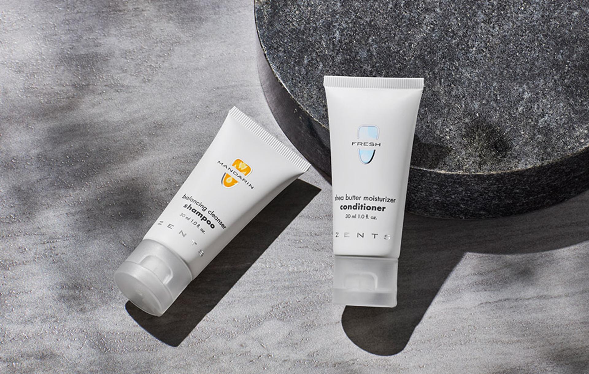 Zents Shampoo and Conditioner singe-use amenities laying flat on bathroom vanity