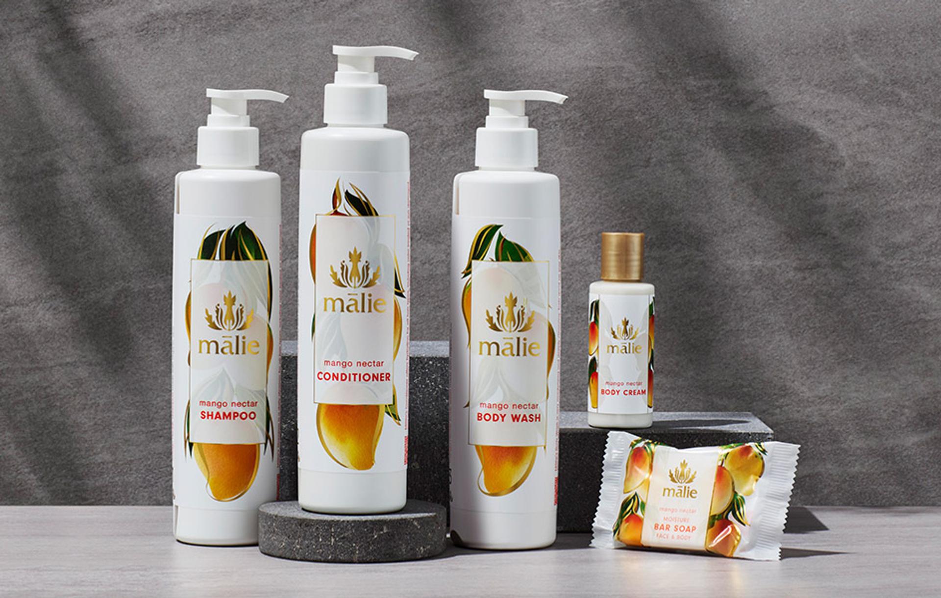 Malie Mango Nectar Shampoo, Conditioner and Body Wash dispensers with Body Lotion singe-use bottle and bar soap on counter