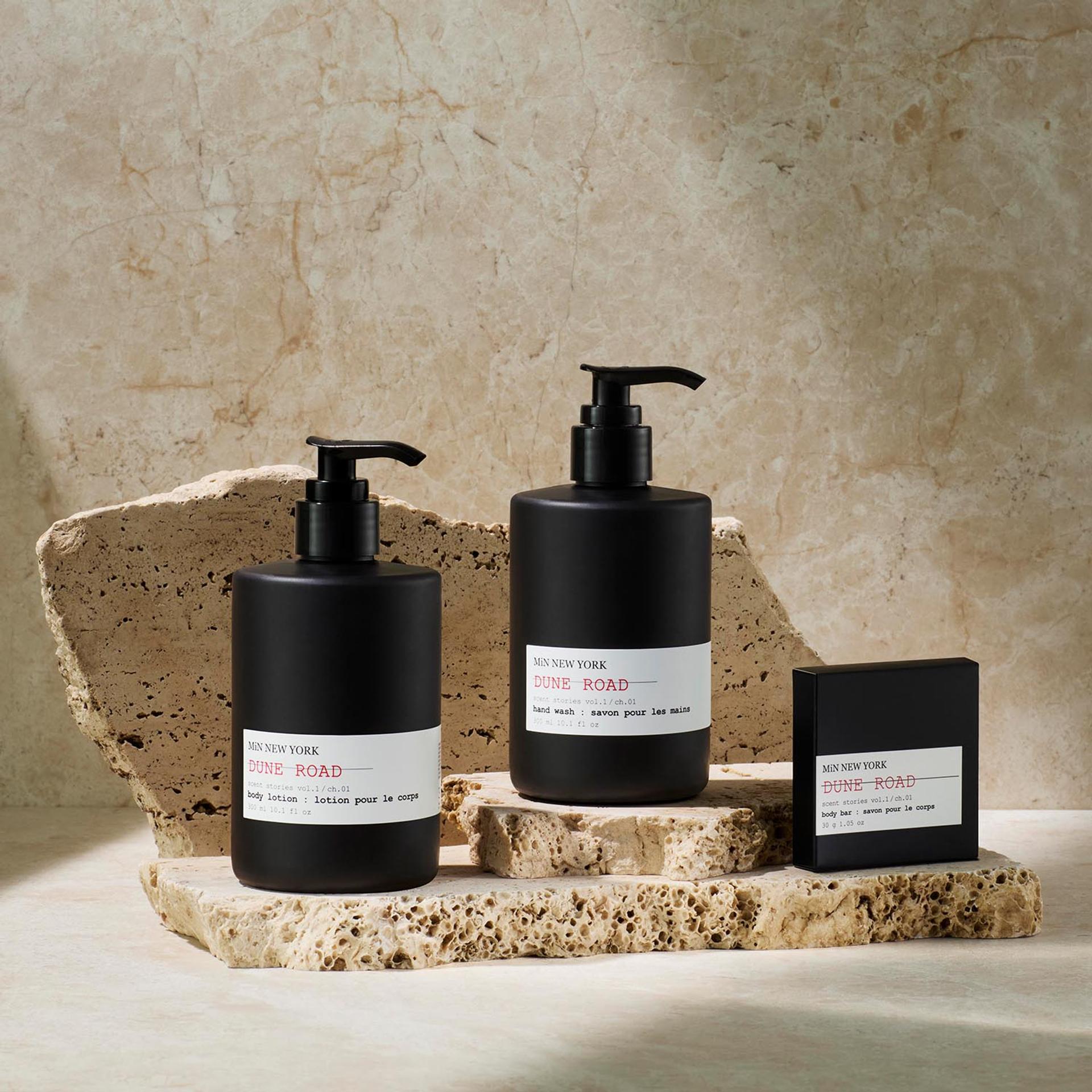 MiN New York Dune Road Body Lotion and Hand Wash dispensers and Bar Soap on counter with sandstone background