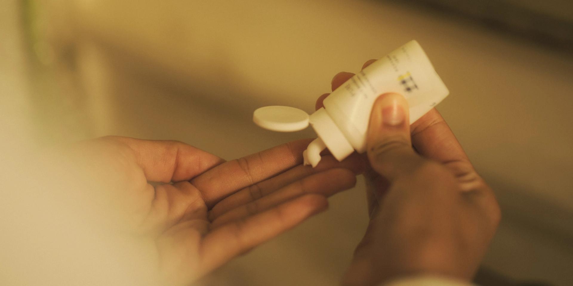 Model squeezing Beekman 1802 Pure Body Lotion from small format bottle into hand