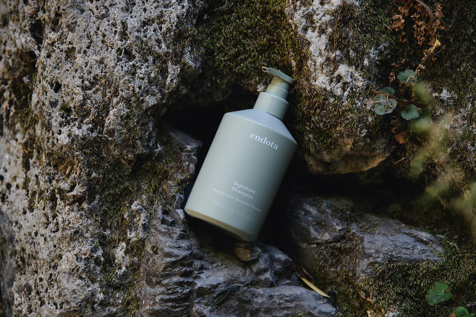endota Signature Shampoo lying on rocks outdoors