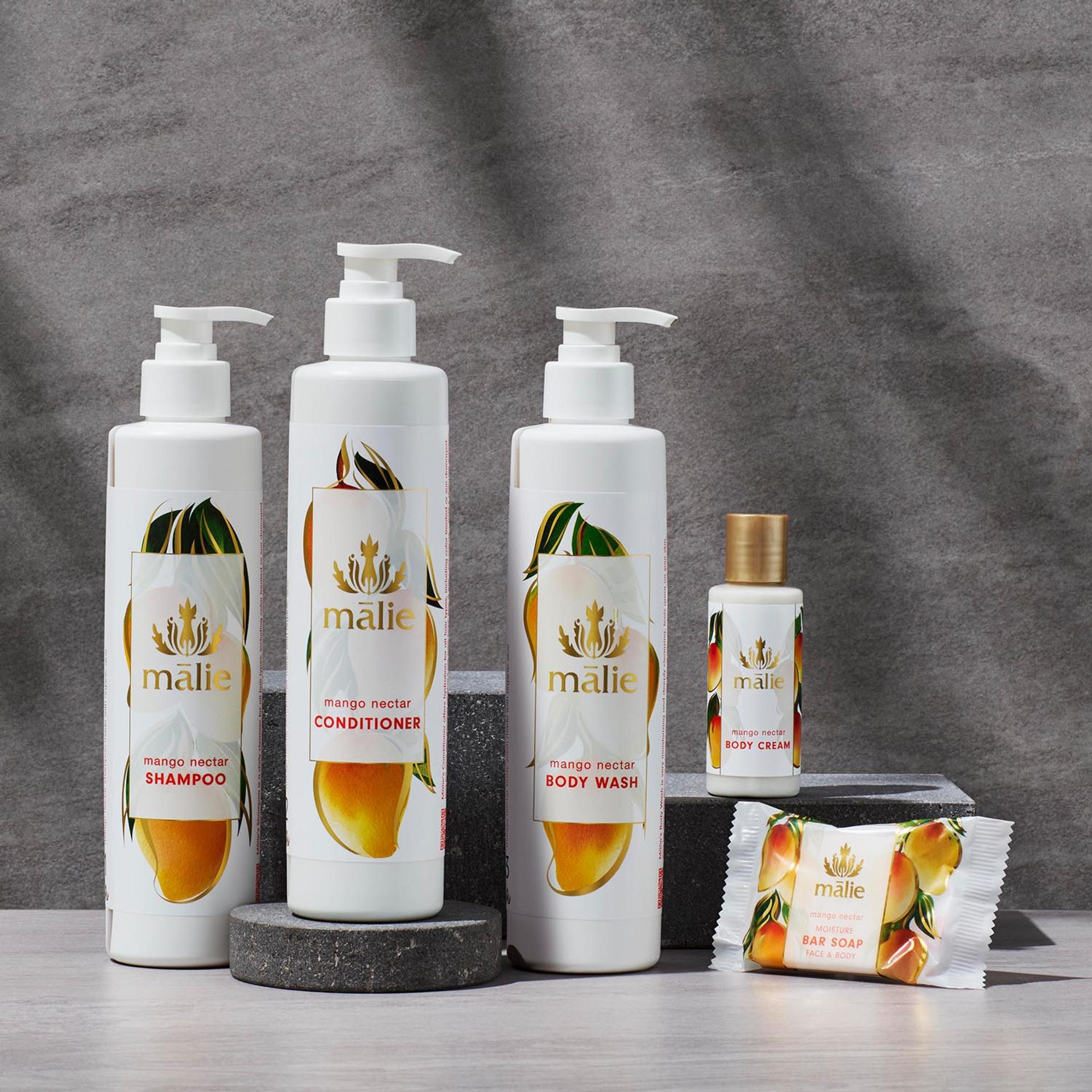 Malie Mango Nectar Shampoo, Conditioner and Body Wash dispensers with Body Lotion singe-use bottle and bar soap on counter