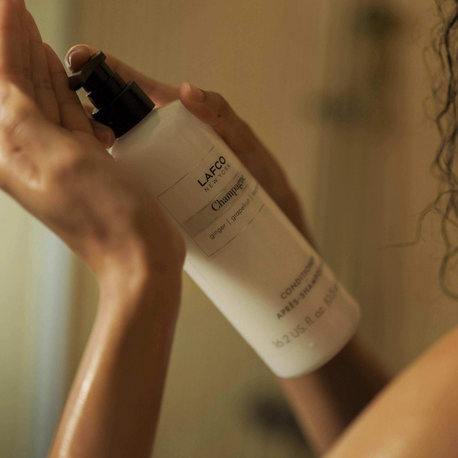 Girl holding Lafco Champagne Conditioner in the shower