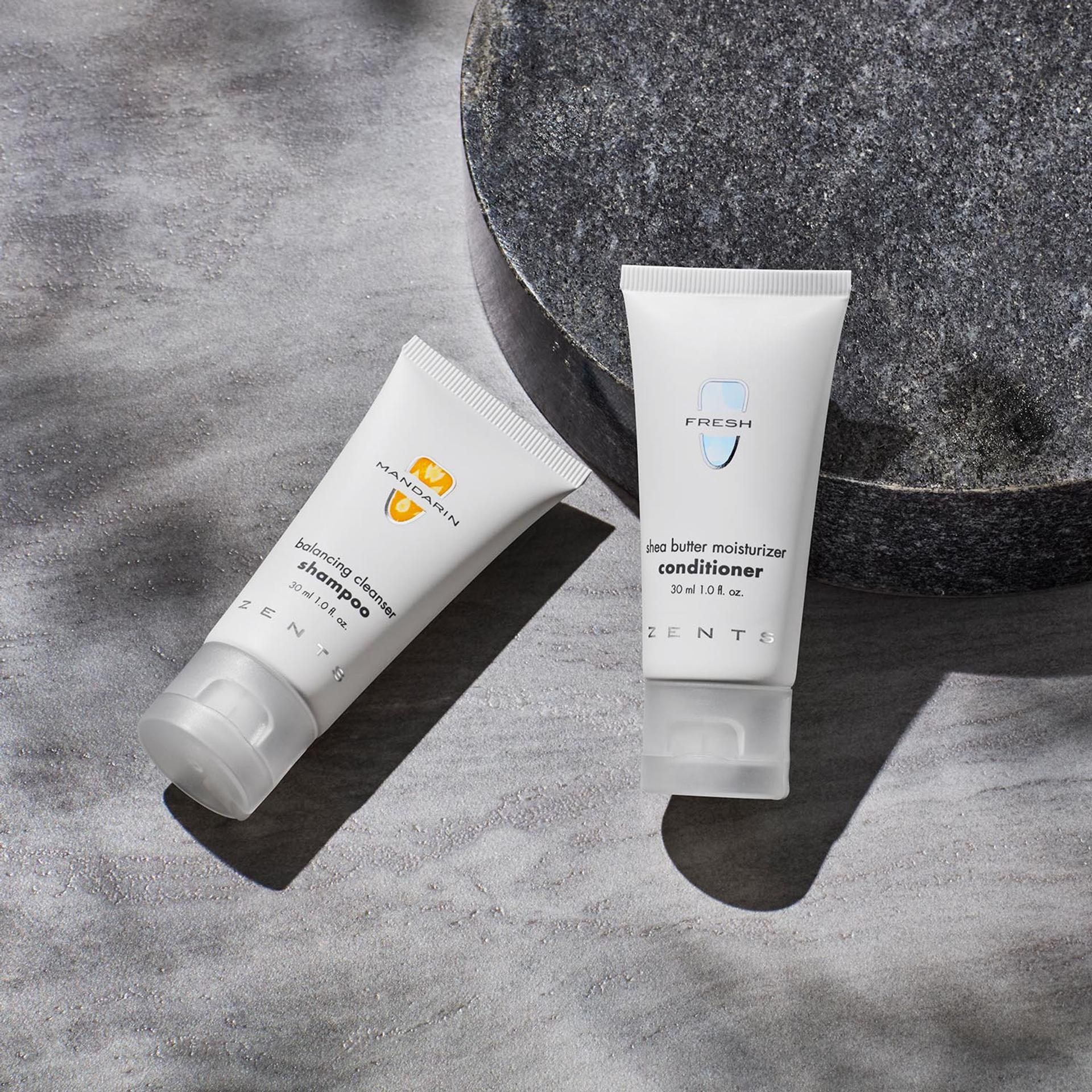 Zents Shampoo and Conditioner singe-use amenities laying flat on bathroom vanity