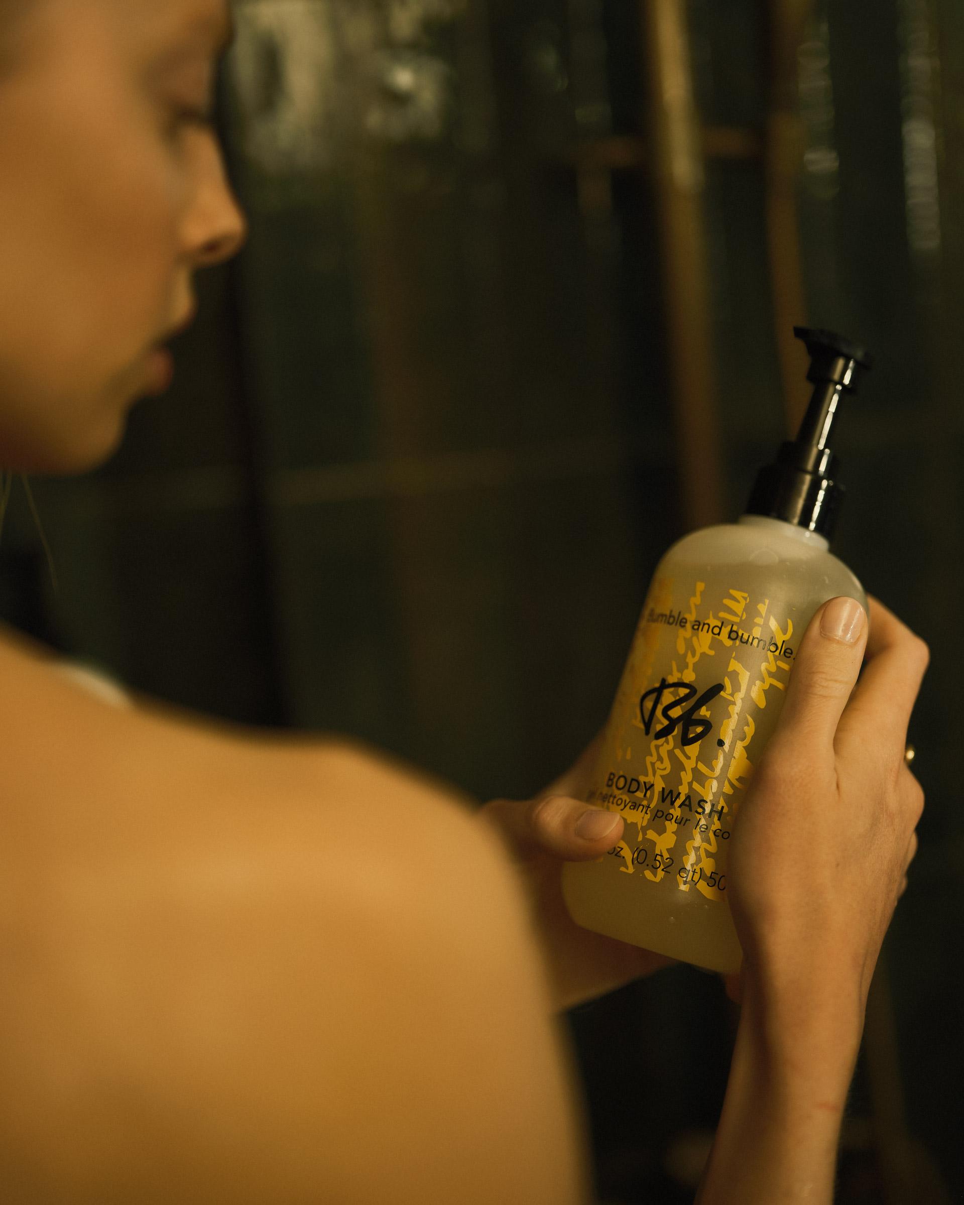 Girl holding a bottle of Bumble & Bumble Body Wash in the shower