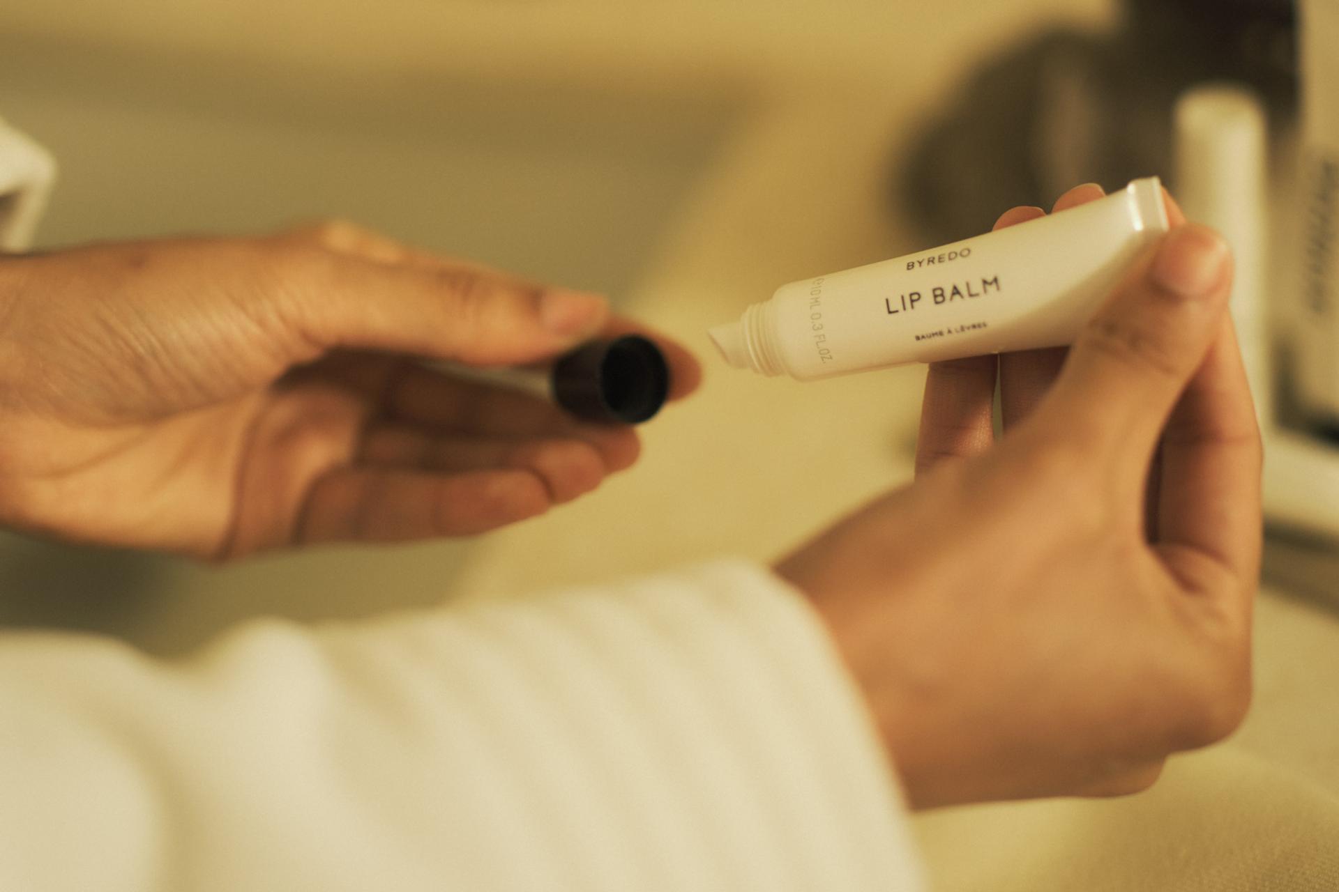 Girl holding Byredo Lip Balm tube with cap off