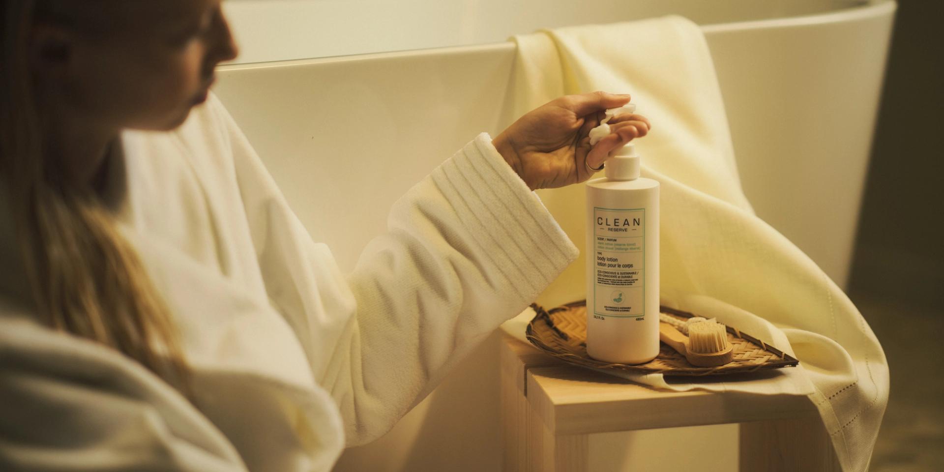 Girl pumping out Clean Reserve Body Lotion in bathroom next to bathtub