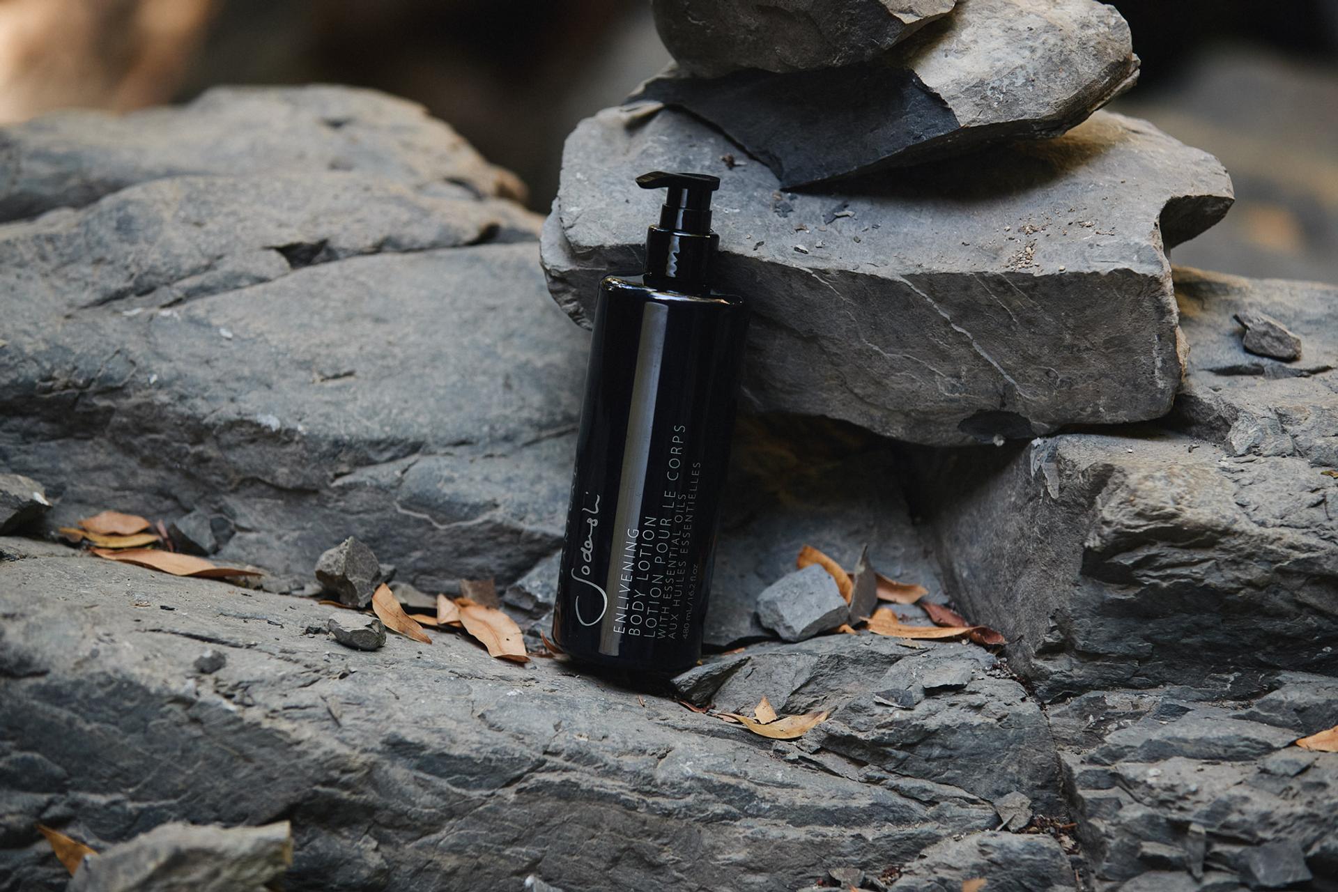 Sodashi Enlivening Body Lotion dispenser on rocks