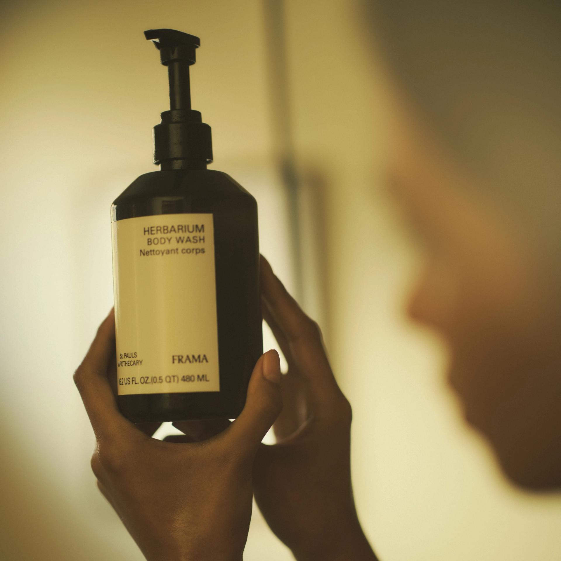 Girl looking at a bottle of Frama Herbarium Body Wash
