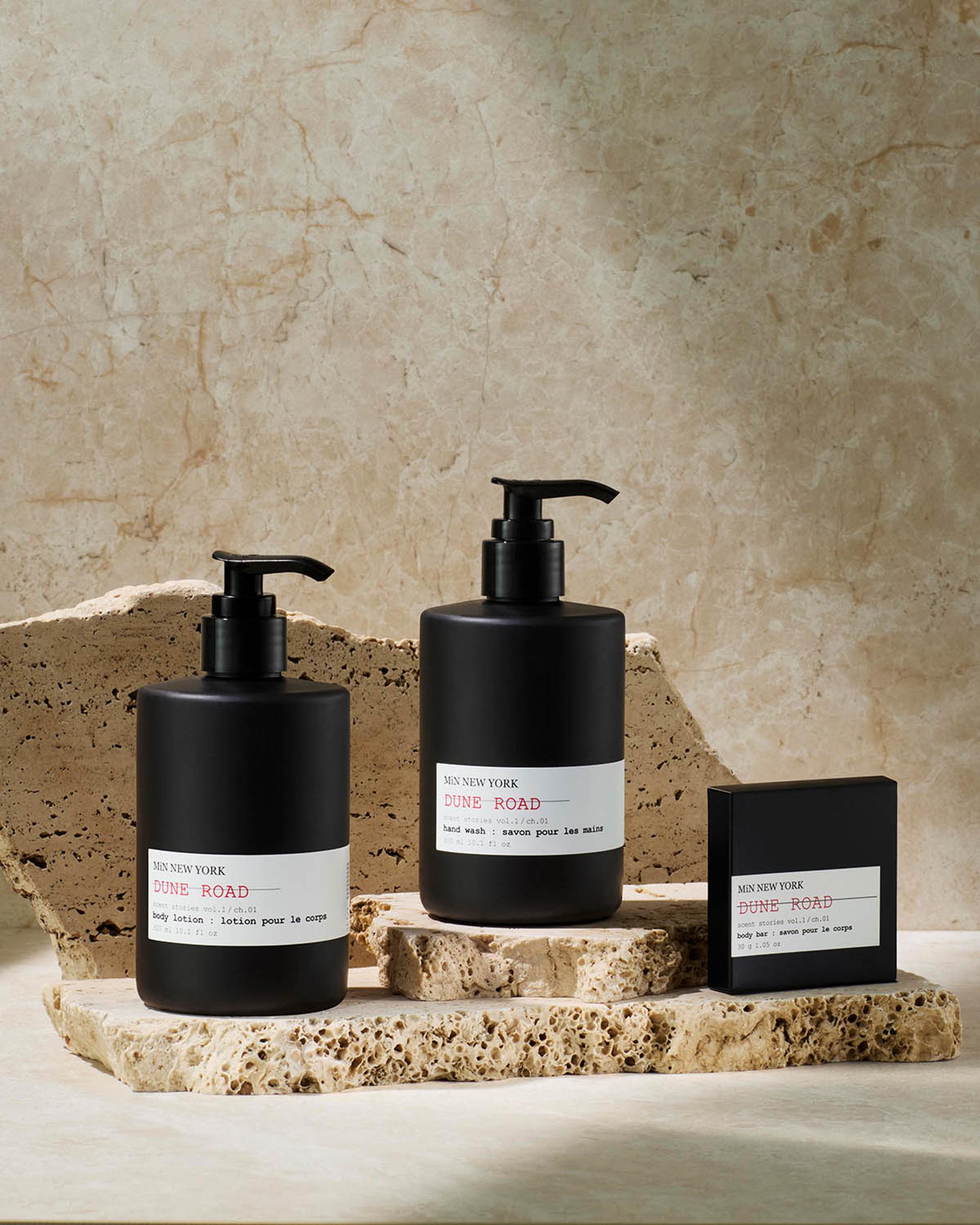 MiN New York Dune Road Body Lotion and Hand Wash dispensers and Bar Soap on counter with sandstone background