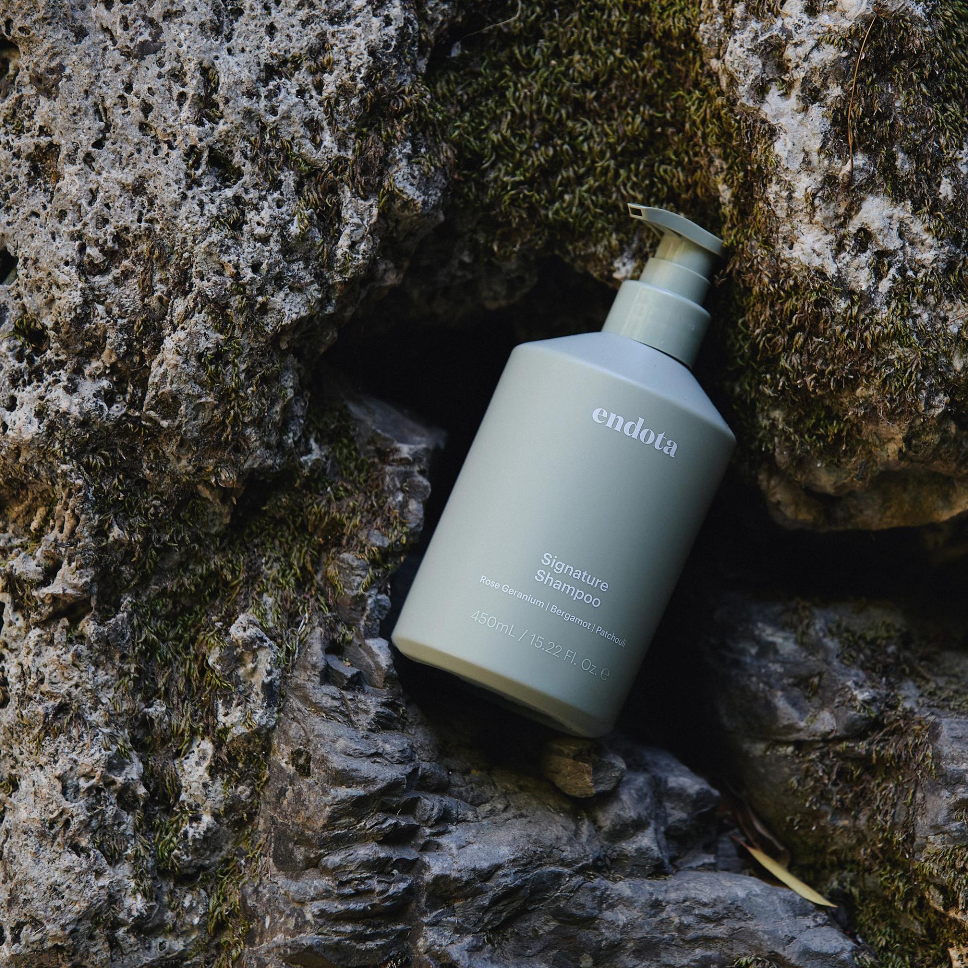 endota Signature Shampoo lying on rocks outdoors