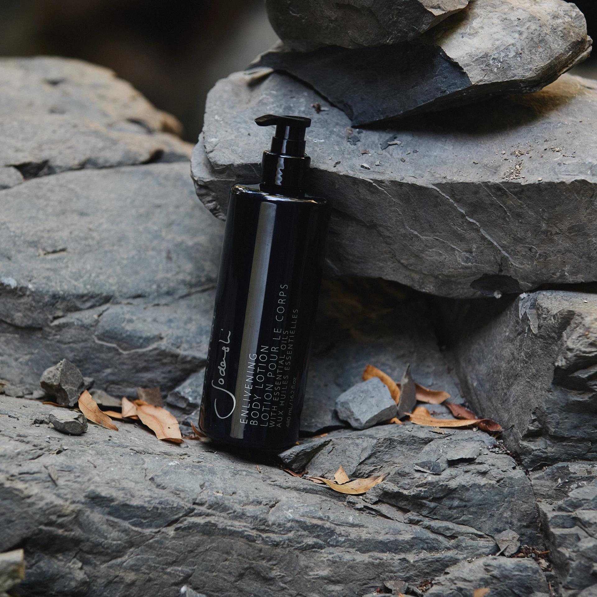 Sodashi Enlivening Body Lotion dispenser on rocks