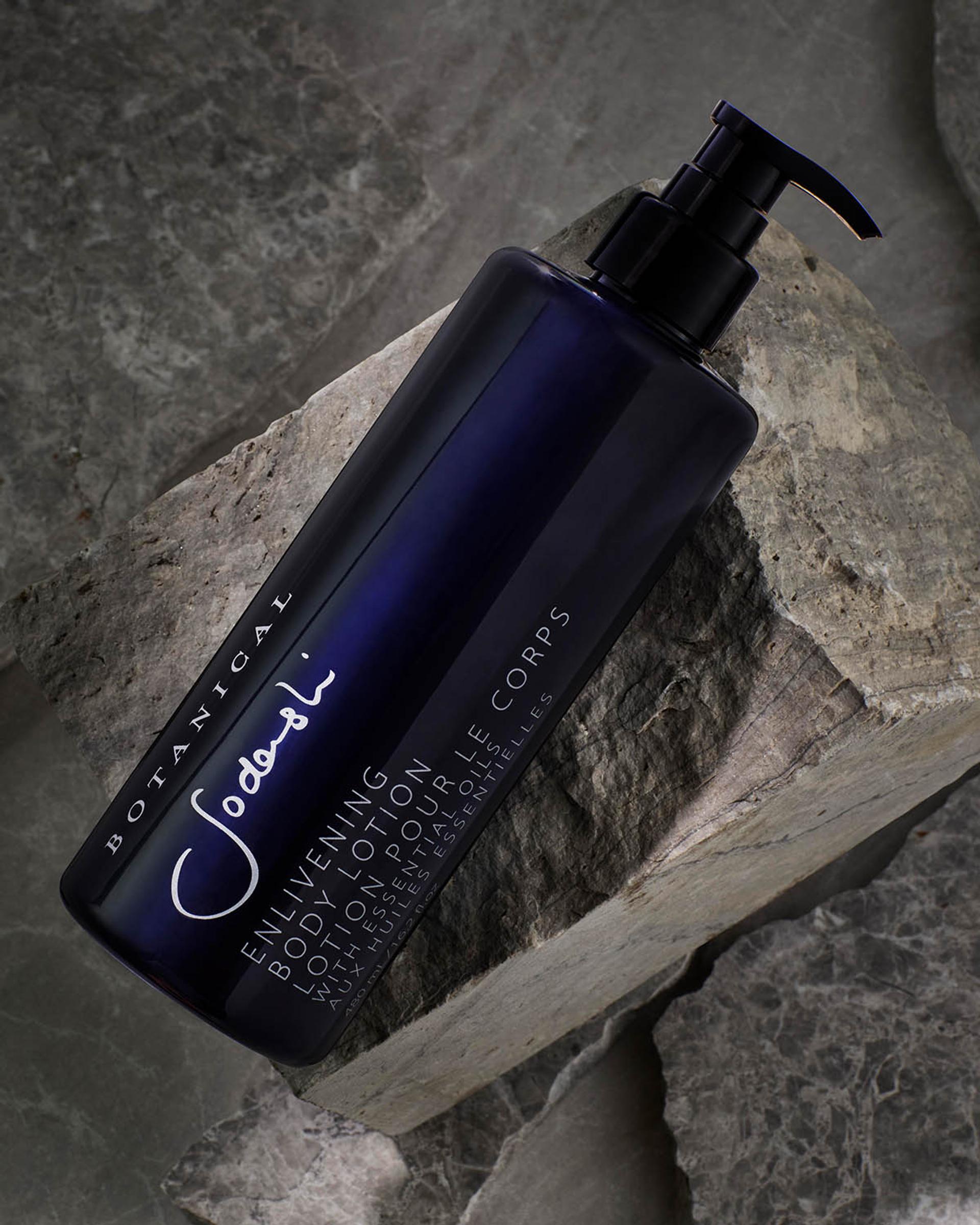 Sodashi Enlivening Body Lotion dispenser laying on stone