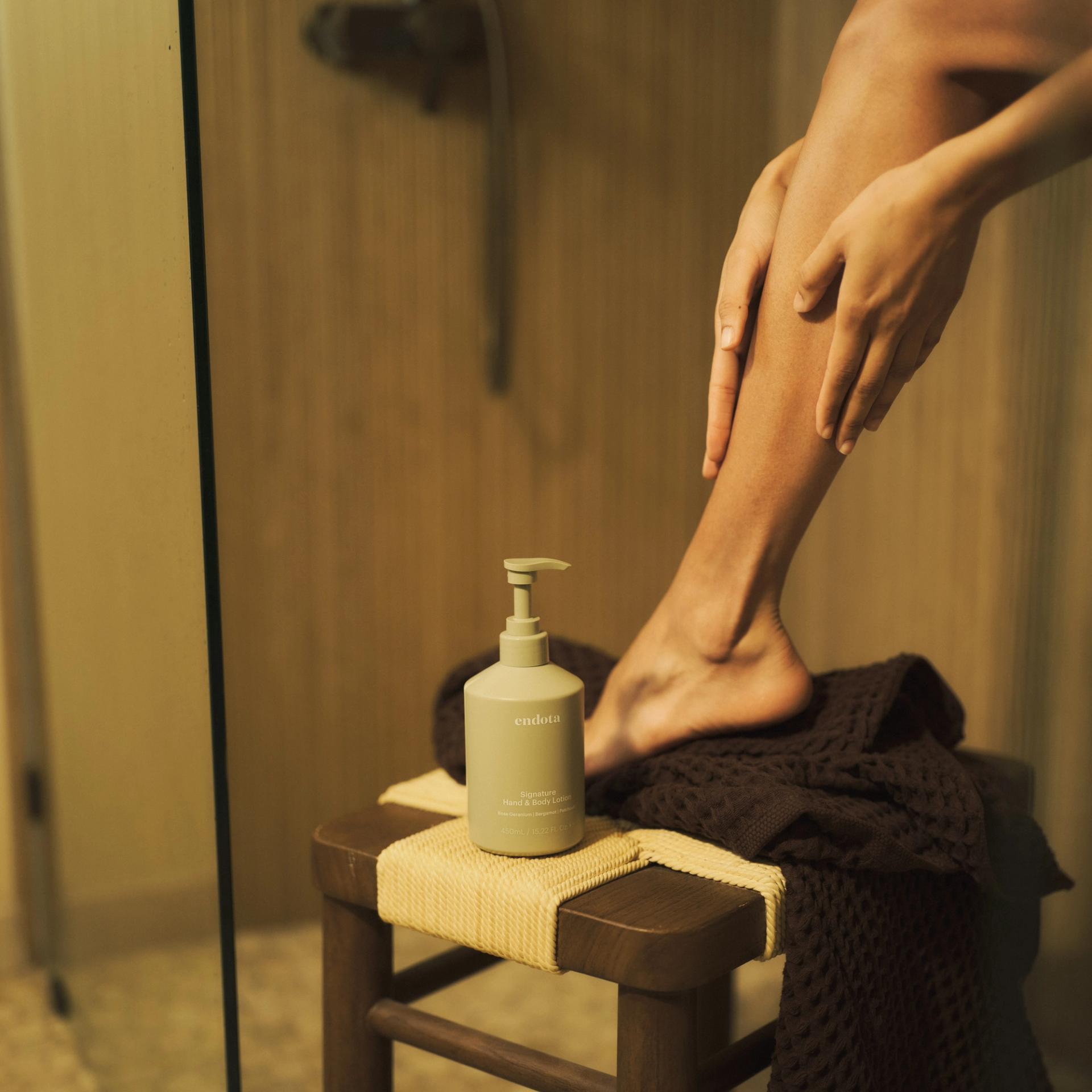 Girl applying endota Signature Hand & Body Lotion in shower